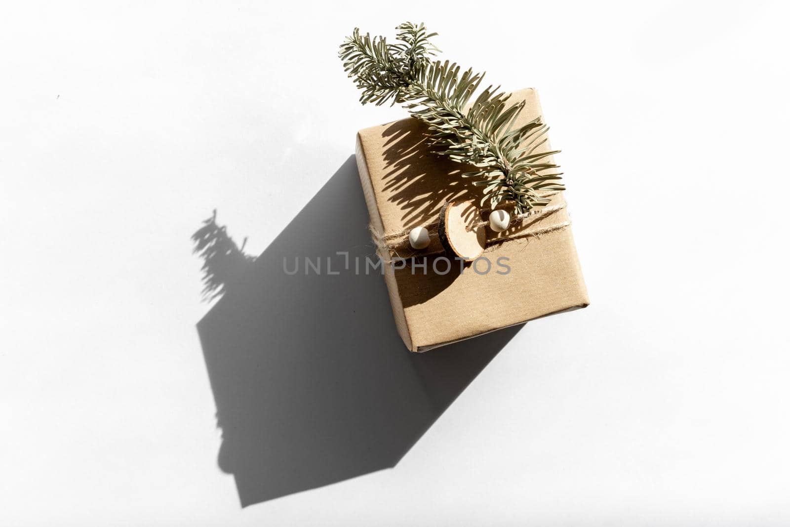 Gift in craft paper on a white with shadow isolated, christmas and zero waste, eco friendly packaging. Ecological Christmas holiday concept, eco decor by photolime