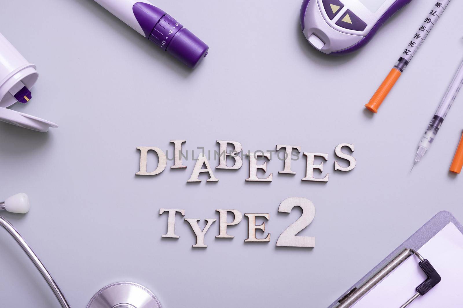 Inscription diabetes type 2 and glucometer, syringes and medical equipment on a colored background, top view.