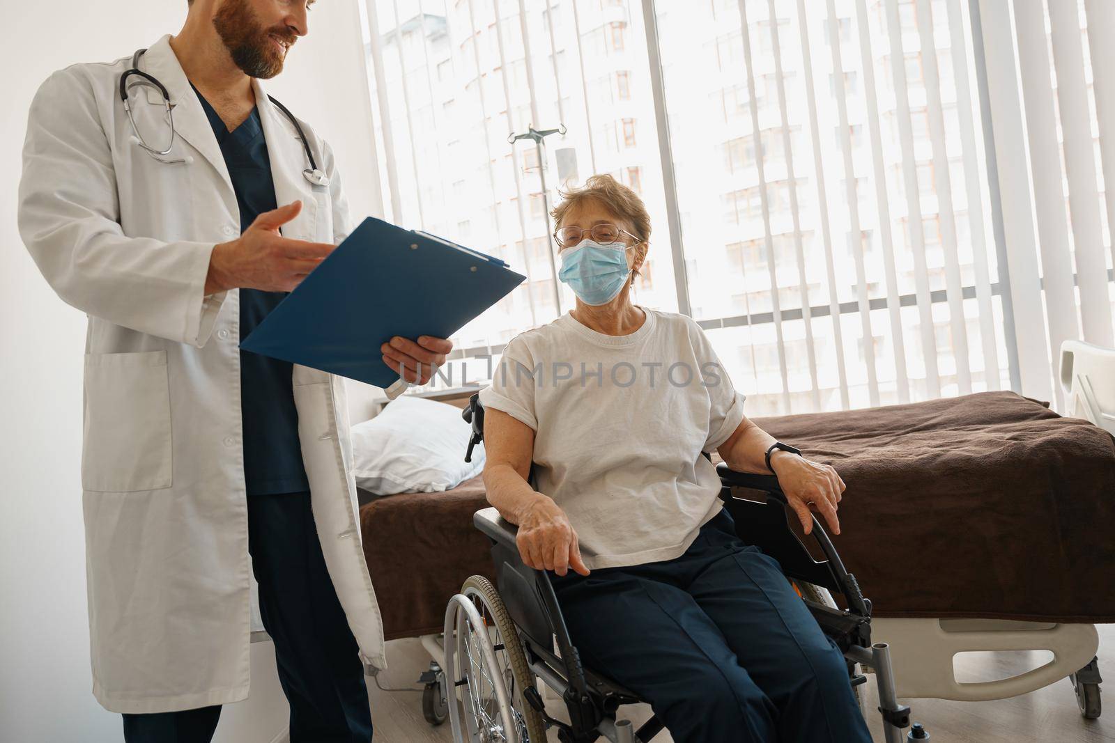 Doctor explaining to a sick patient in wheelchair details of treatment. High quality photo