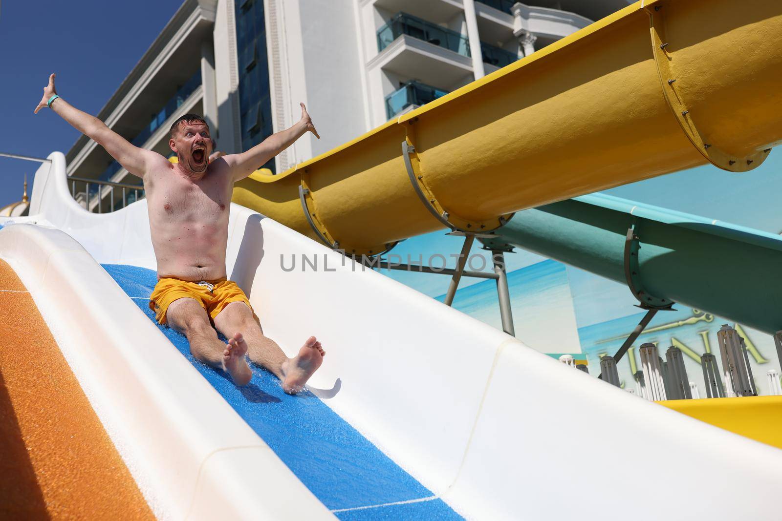 Emotional man screams in horror going down water slide. Testing of opened water park