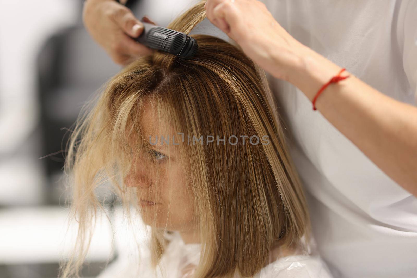 Pulling strands of hair with professional iron care. Keratin straightening and hair restoration