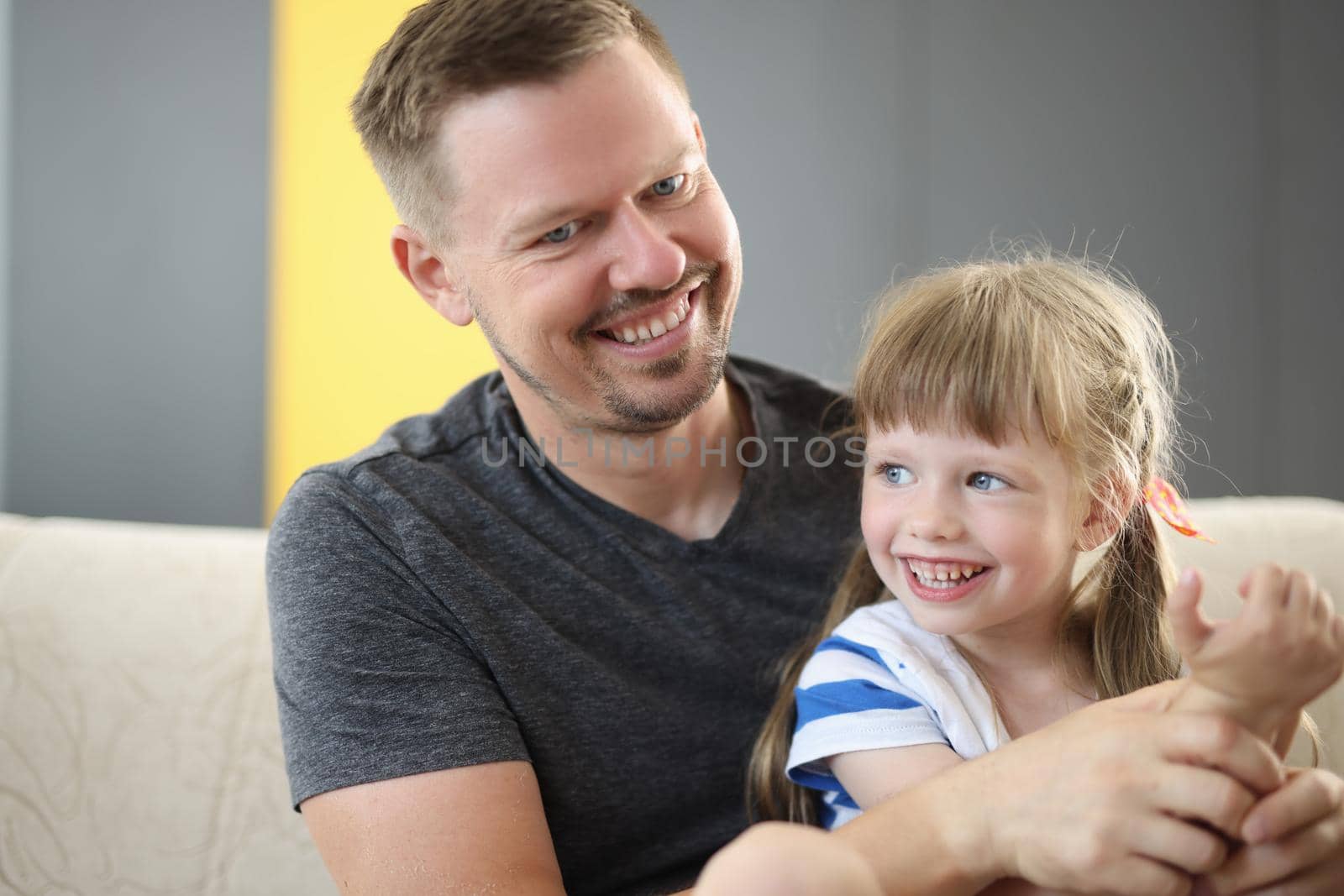 Happy dad holding cute cheerful daughter laughing and having good time together. Loving father and smiling little girl hugging and caring dad