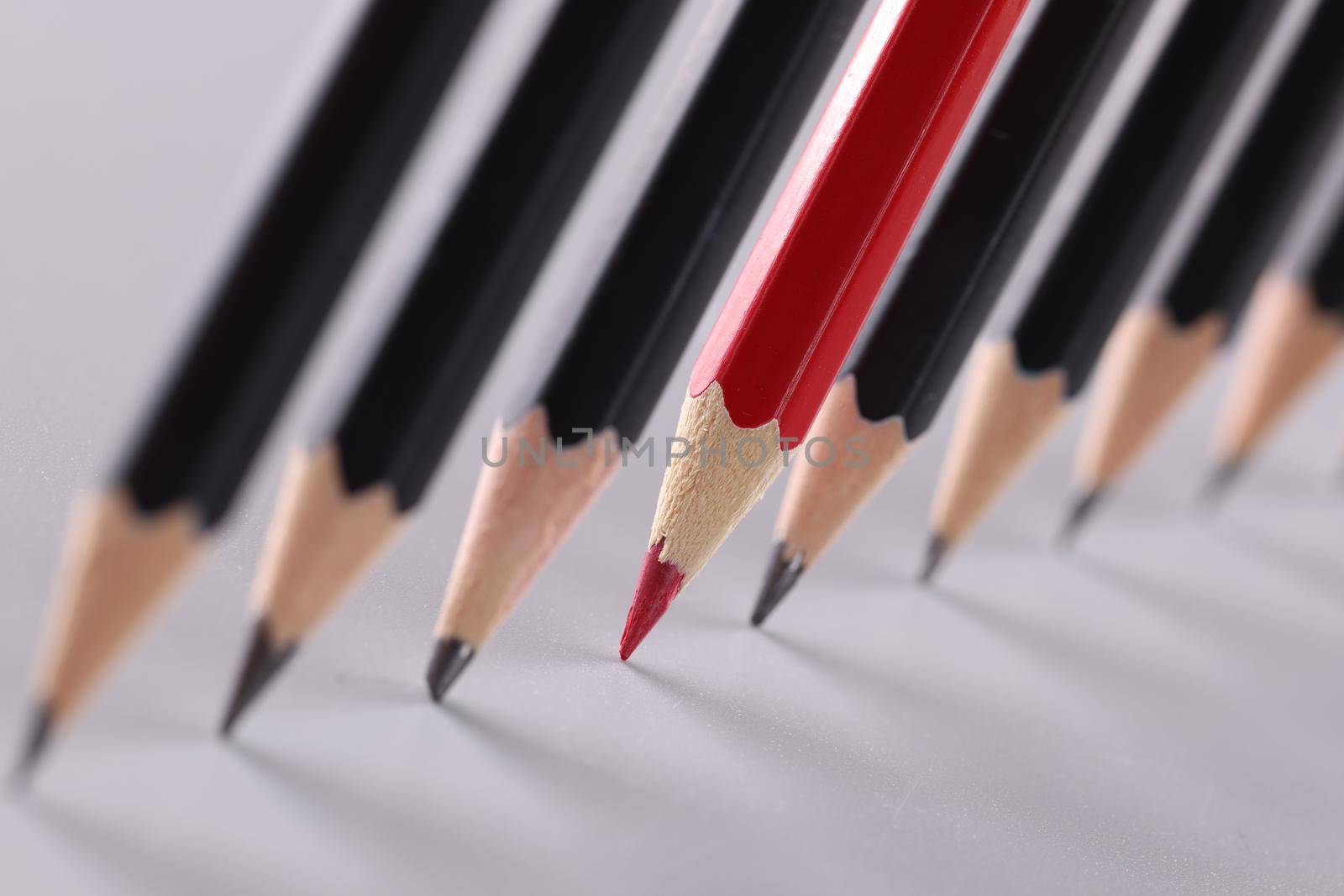 Red pencil separating row of black pencils by kuprevich
