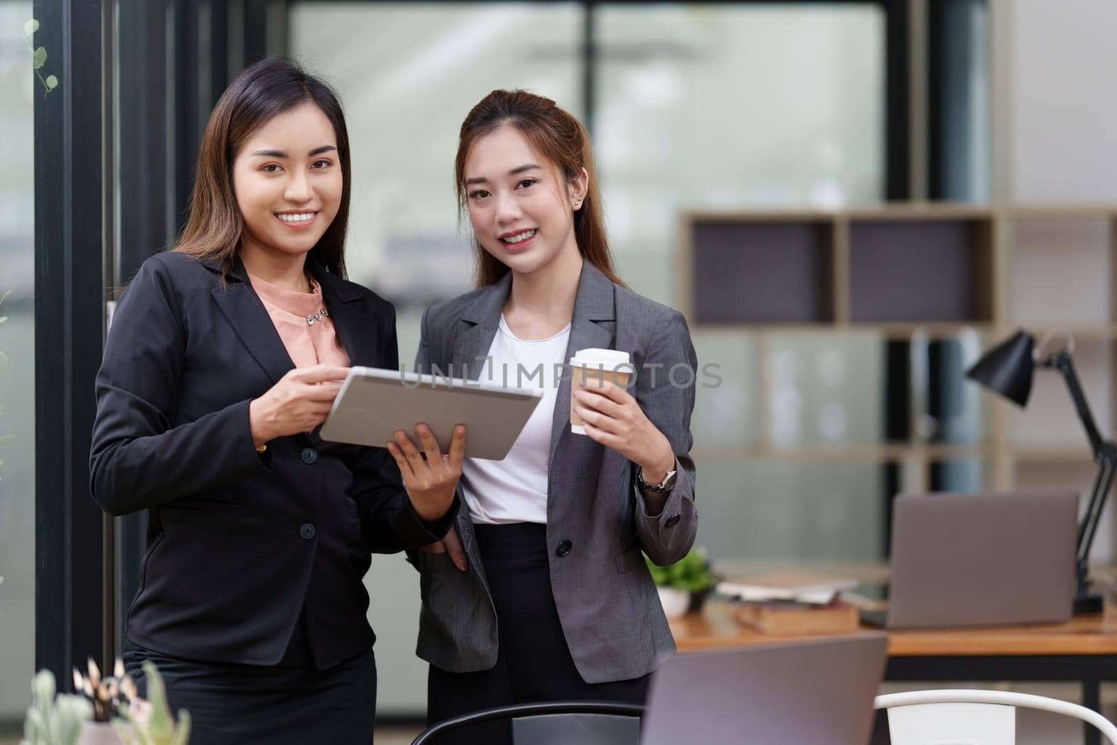 Two Positive Asian secretary smiling to camera during meeting at office