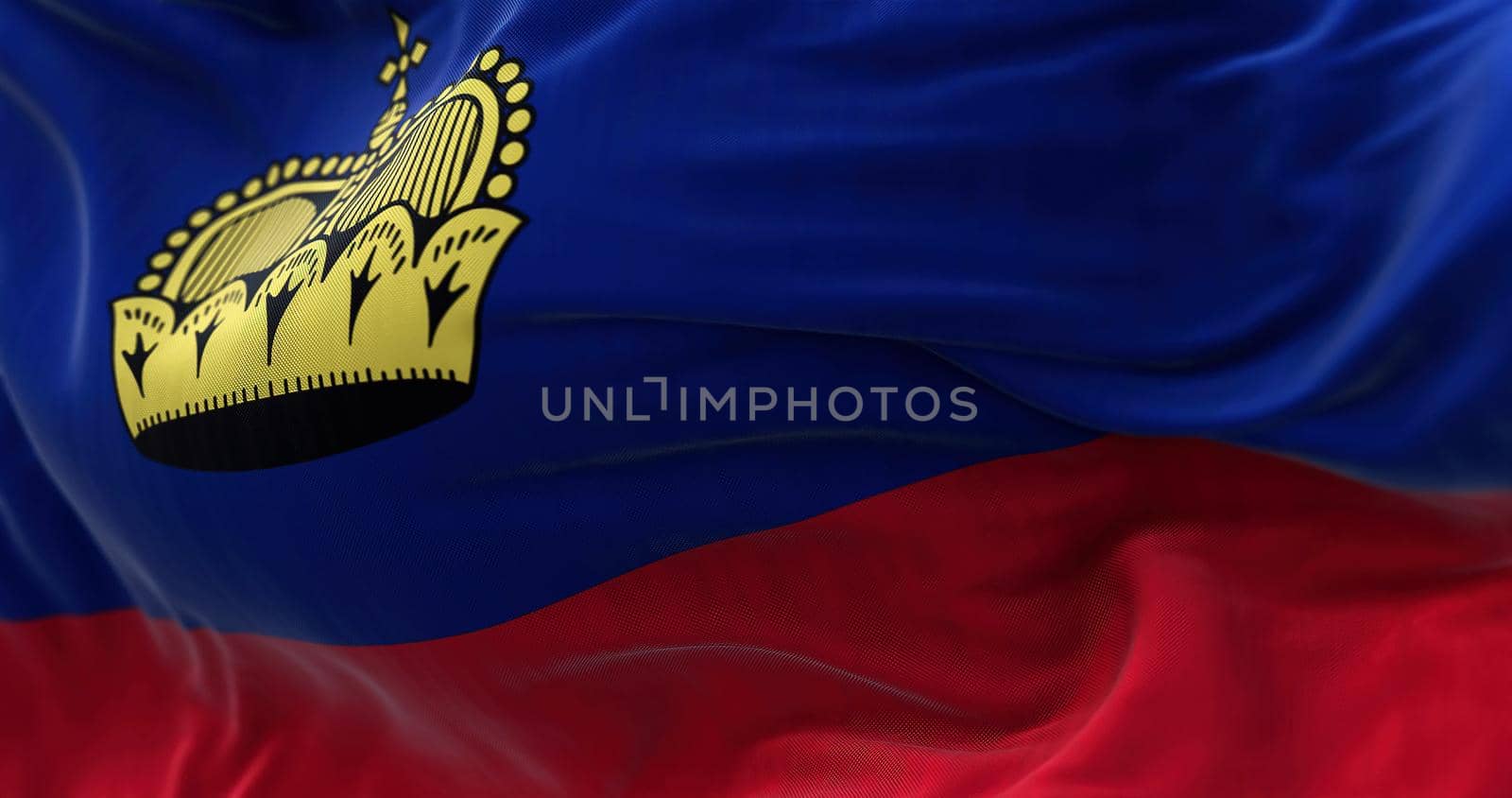 Close-up view of the Liechtenstein national flag waving in the wind. The Principality of Liechtenstein is a microstate located in the Alps. Fabric textured background. Selective focus