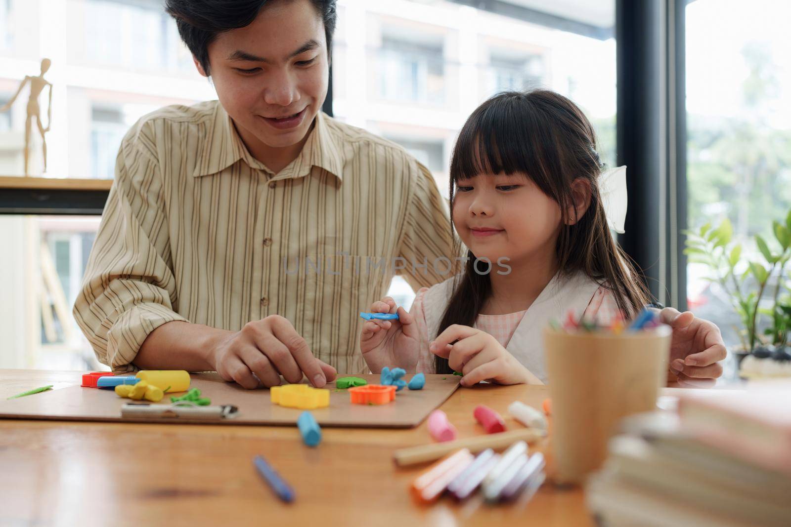 Adorable little girl and father playing with colorful plasticine. Handmade skills training by itchaznong