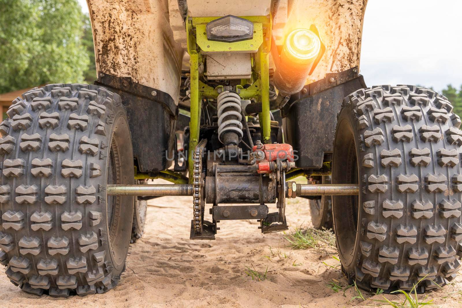 Rear view of the ATV standing on sandy ground. Wheels and suspension of the all-terrain vehicle. The concept of travel and adventure. shock absorbers, brakes, exhaust pipe, axles, chain, gear