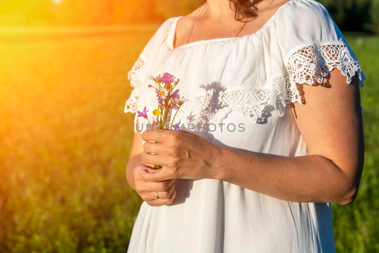 woman in a white dress holds a bouquet of wildflowers in her hands by audiznam2609