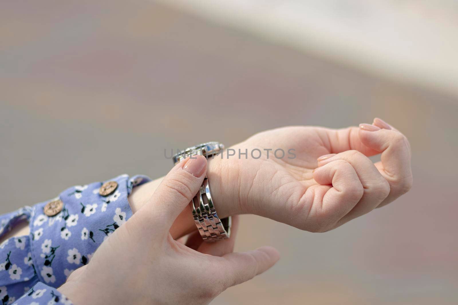 selective focus, beautiful bokeh. female hands. The female fastens her watch. woman puts on a watch. Wrist bracelet. woman fixing accessory. High quality photo