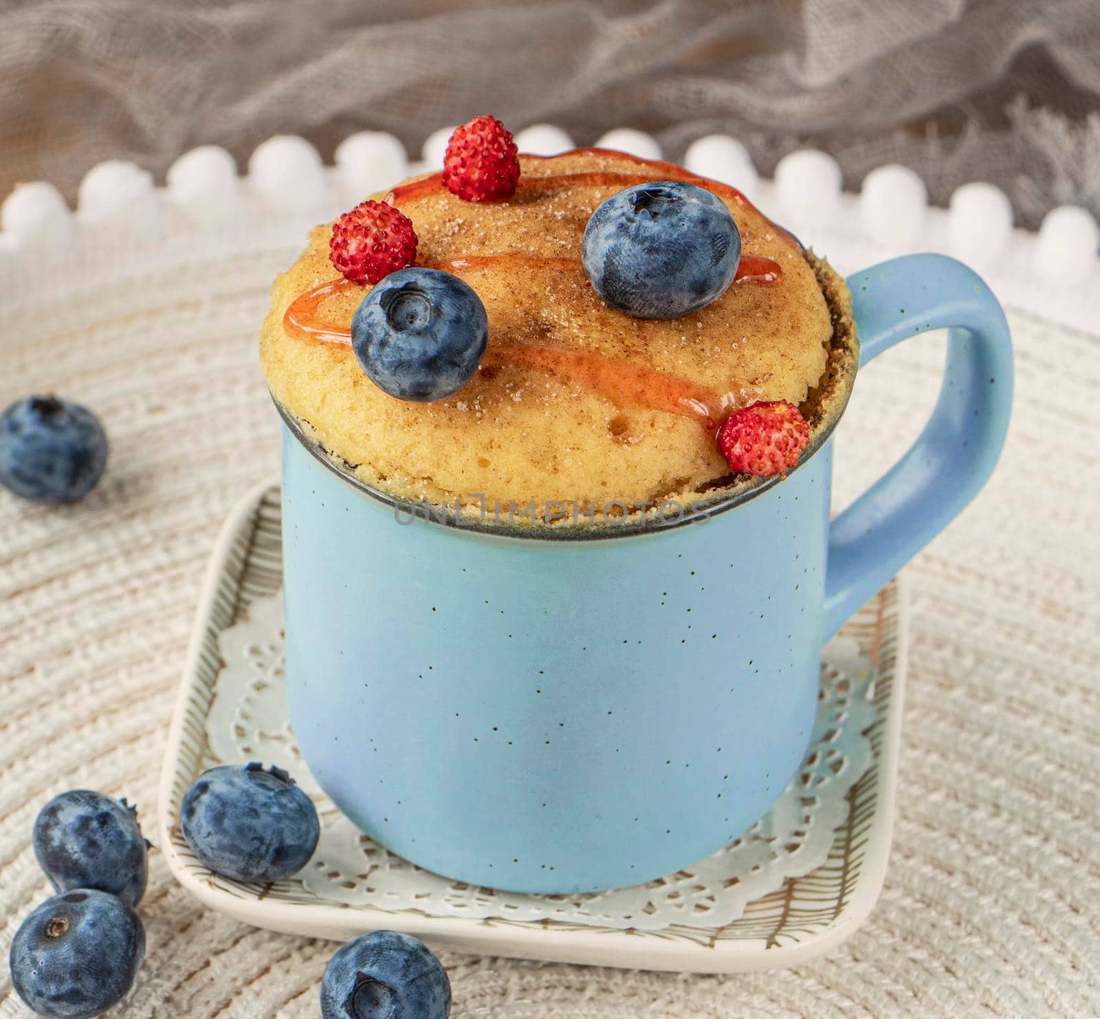 Delicious homemade blueberry muffin mug cake with fresh berries . Cooked in a cup in the microwave. cupcake in a blue mug decorated with blueberries. vanilla mugcake dessert. Easy to cook concept