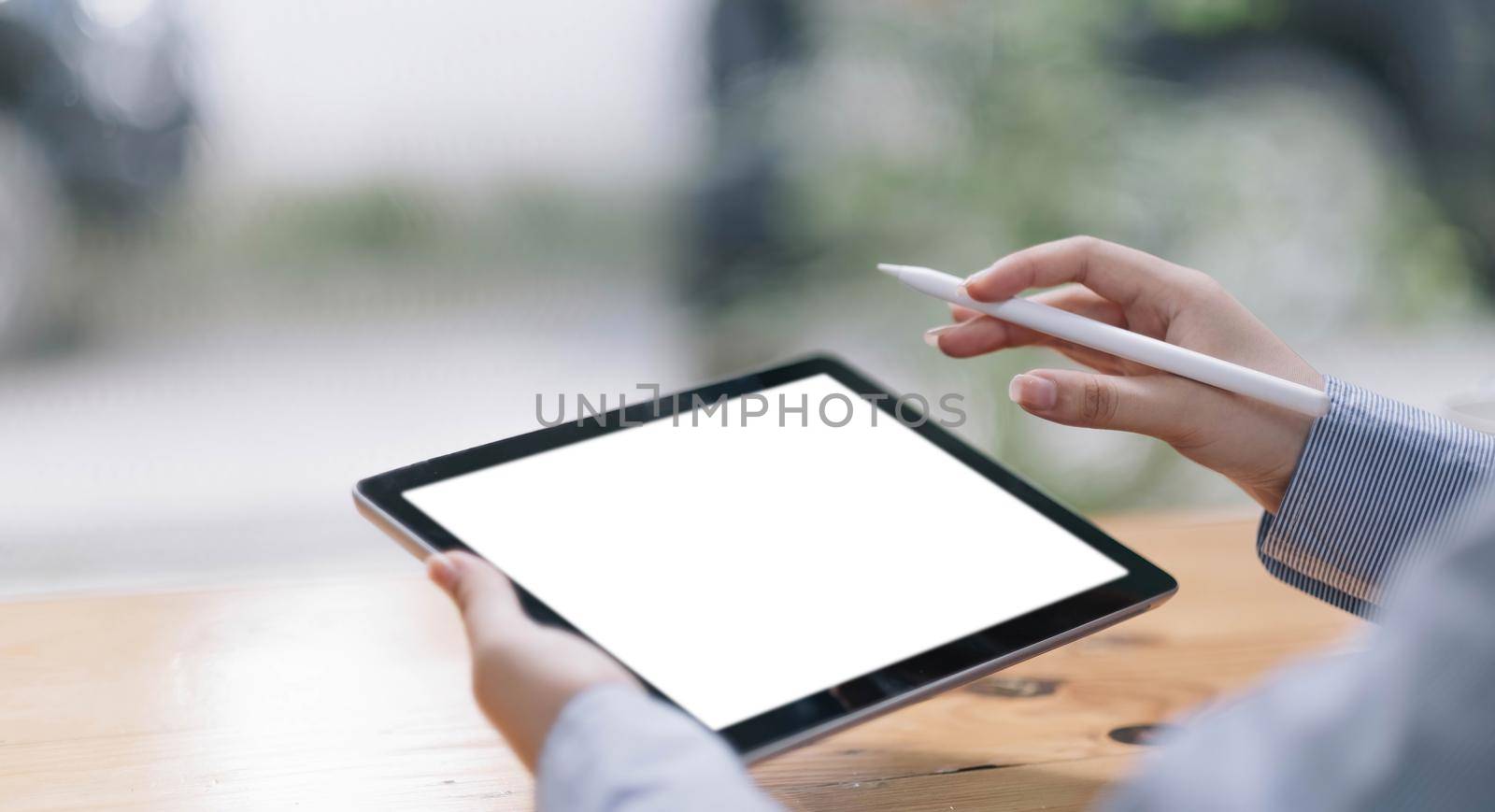 Closeup of woman hand holding digital tablet on the table and the screen is blank..