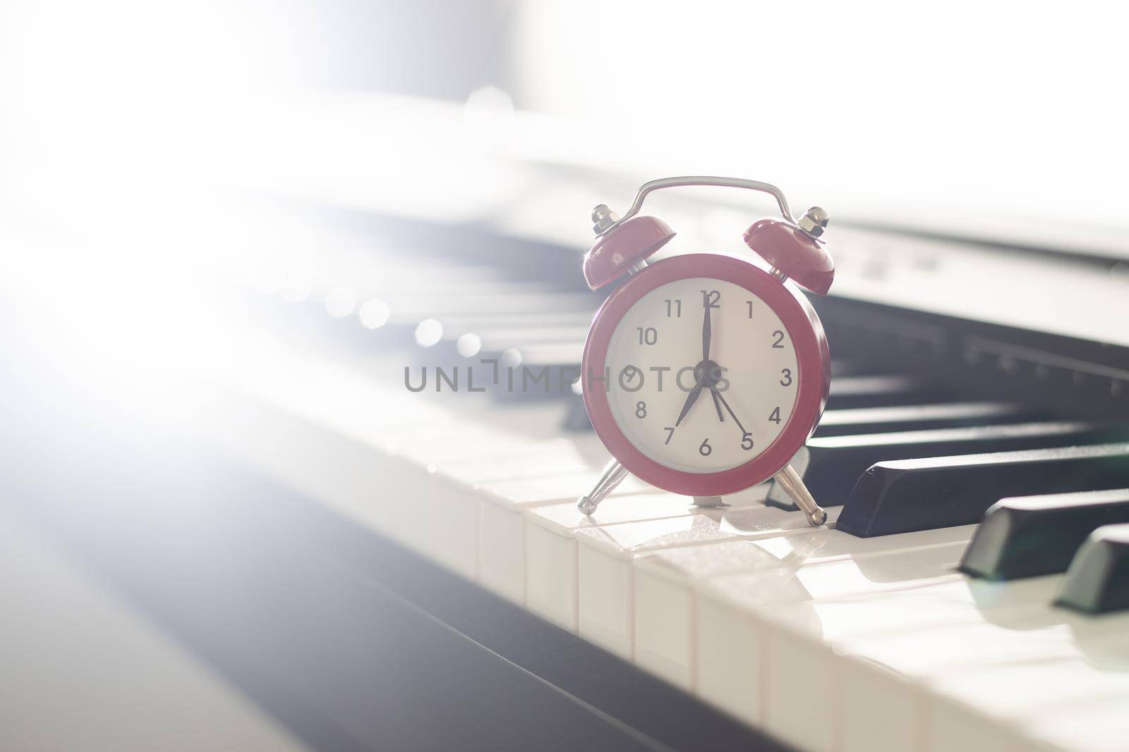 Alarm clock on piano background. Music lesson.