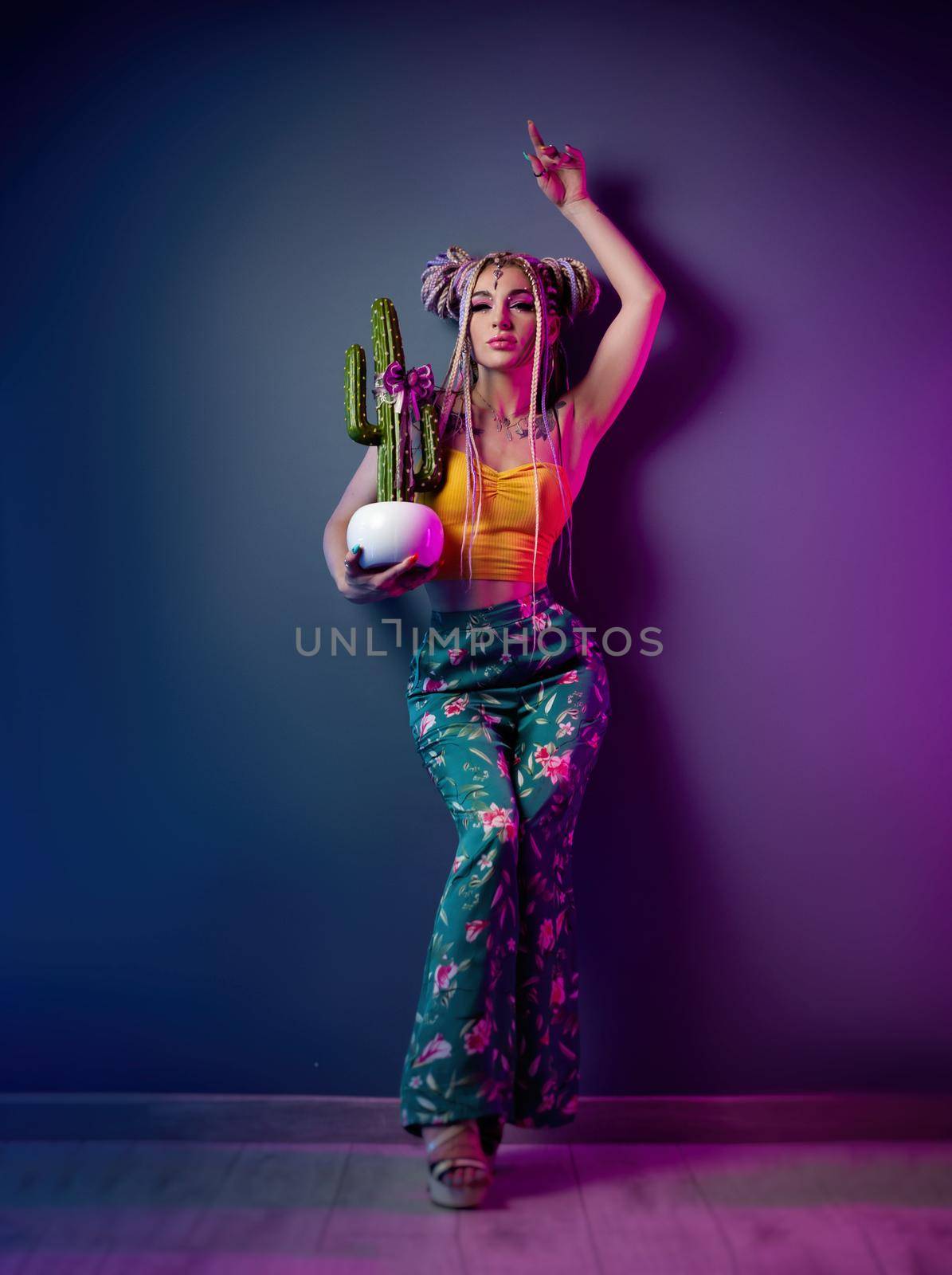 the stylish girl with dreadlocks in fashionable bright clothes on a neon background