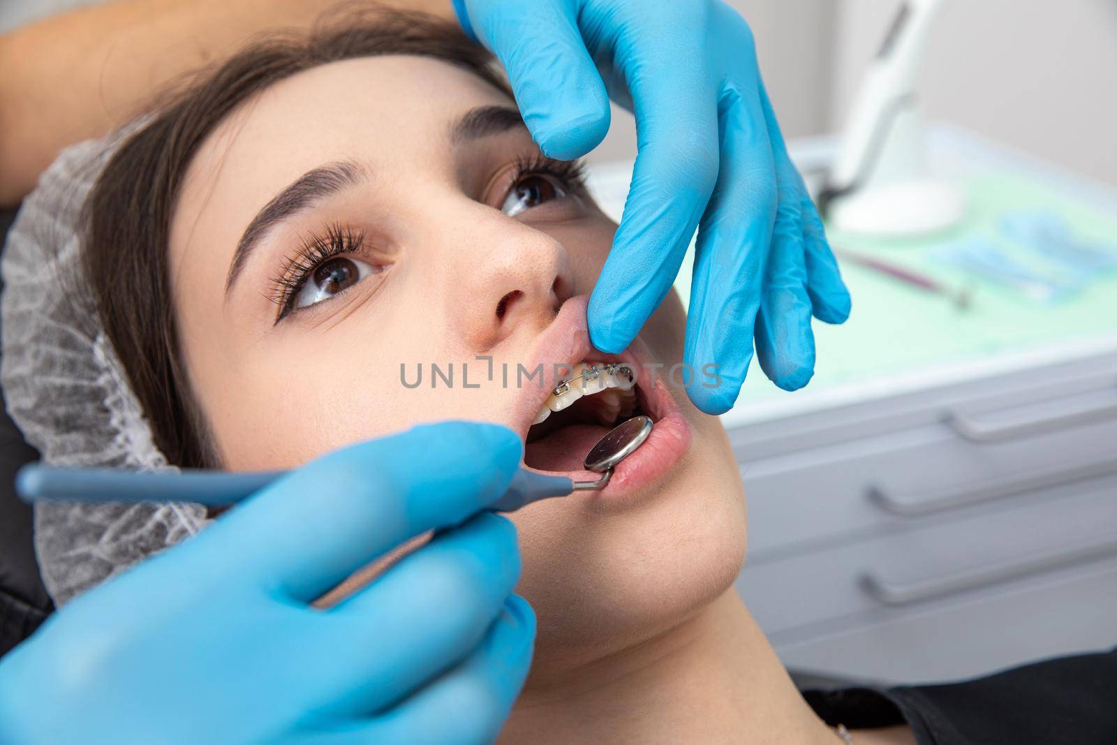 Dentist examining patient teeth with dental mirror. Dental check up concept by Mariakray