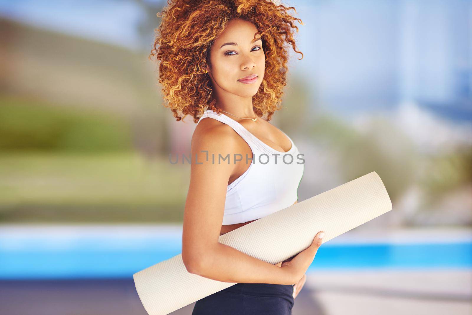 My mat is my canvas and yoga is my art. a sporty young woman holding her yoga mat. by YuriArcurs
