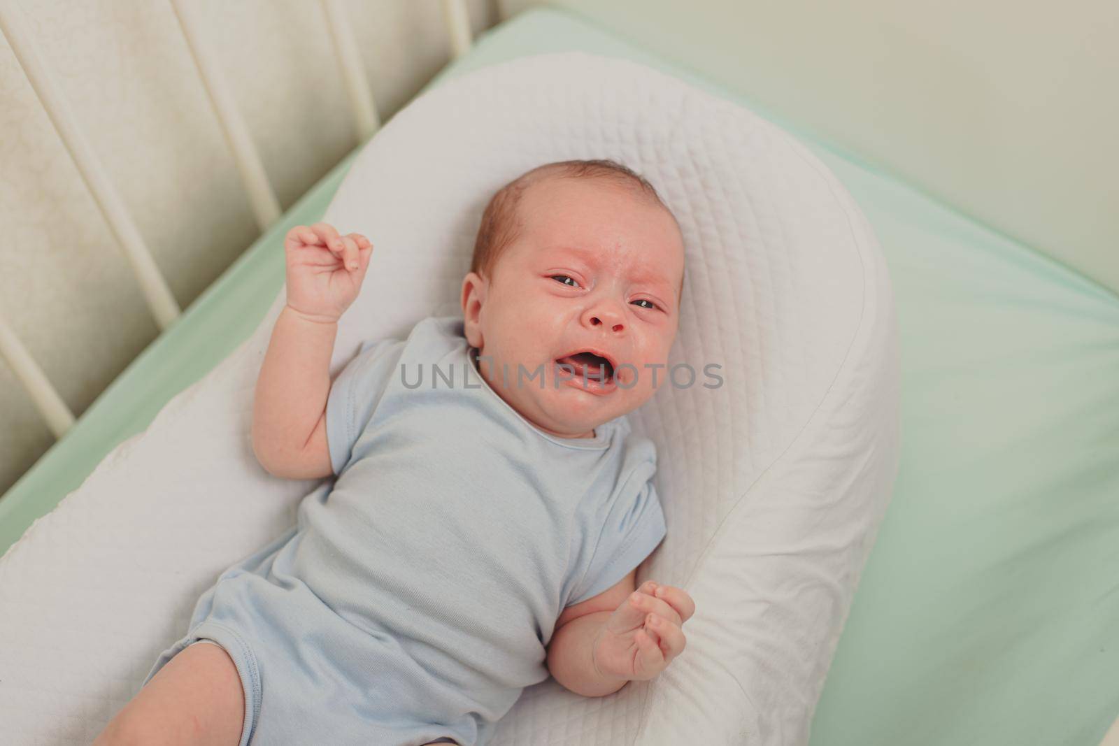 A hungry baby is crying in the crib . Baby crying. Children 's emotions . Pain during teething. A hungry child. Children's colic in the stomach. Lifestyle