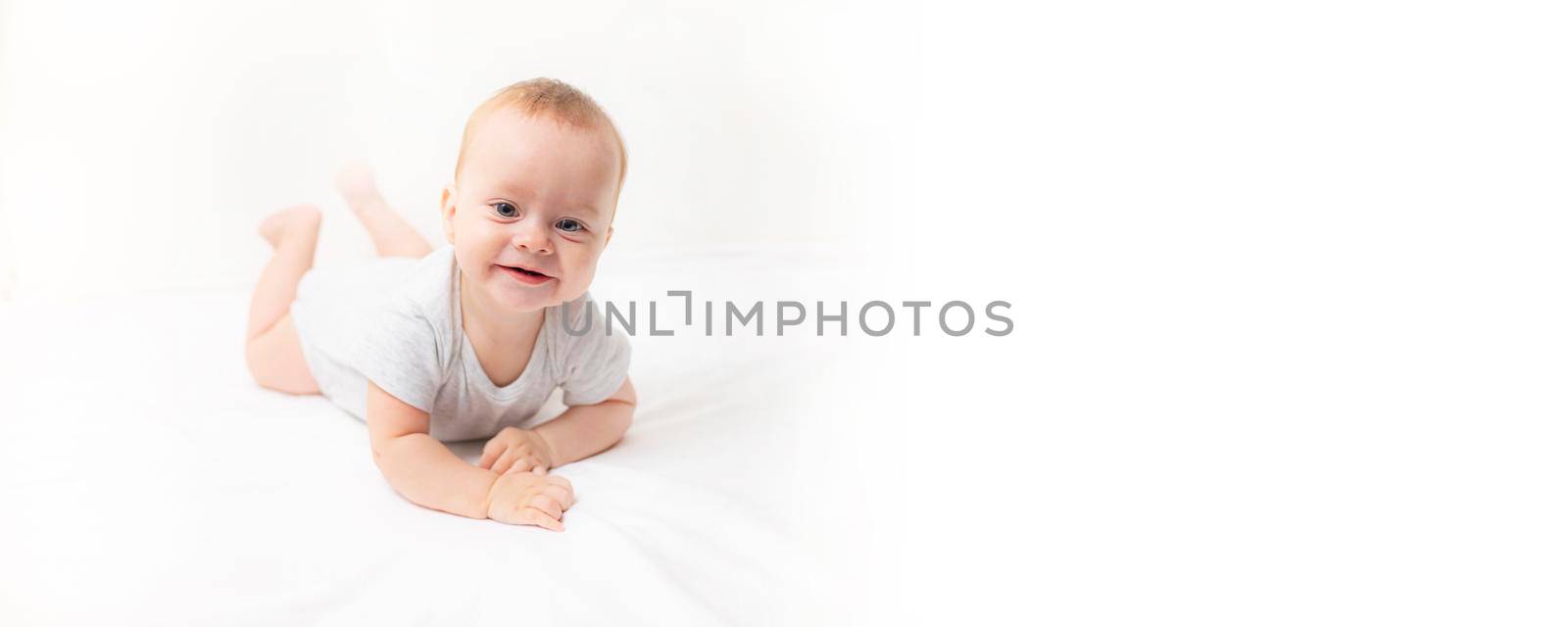 The baby lies on a white background and smiles at the camera . Advertising of children's goods. A child on a white background. Happy baby. The smile of a child. Children 's article . by alenka2194