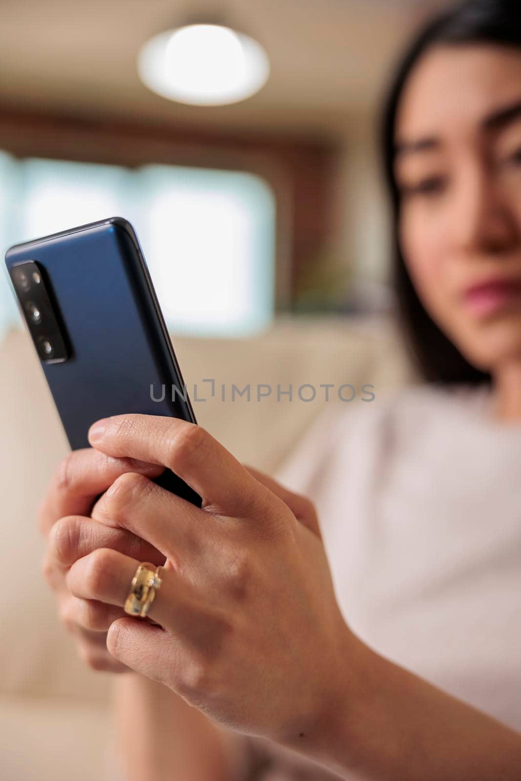 Casual happy asian woman using smartphone at home by DCStudio
