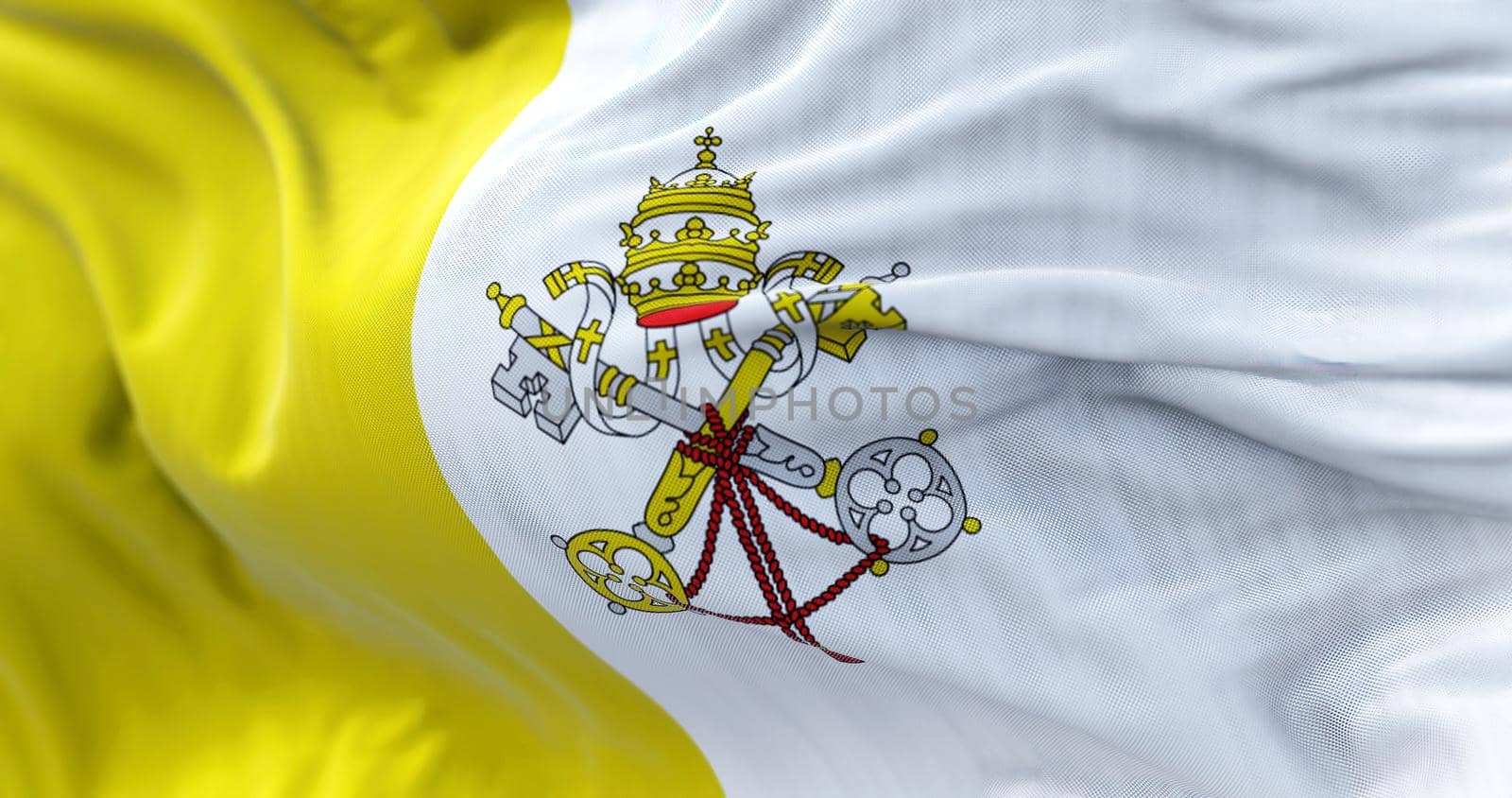 Close-up view of the Vatican national flag waving in the wind. The Vatican City is an independent city-state and enclave surrounded by Rome, Italy. Fabric textured background. Selective focus