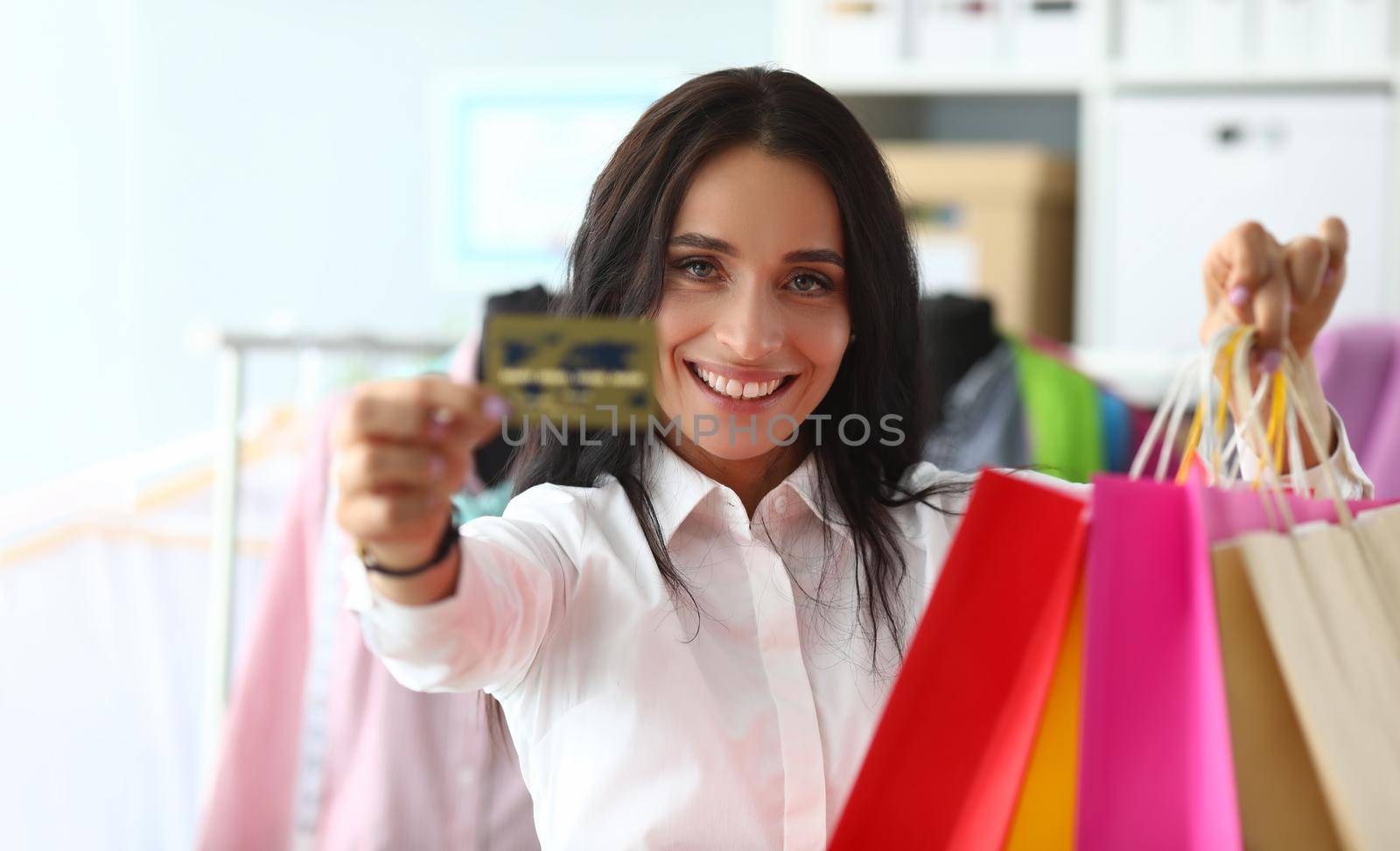 Portrait of woman holding shopping bags in store with bank credit card. Favorable shopping discounts and sales