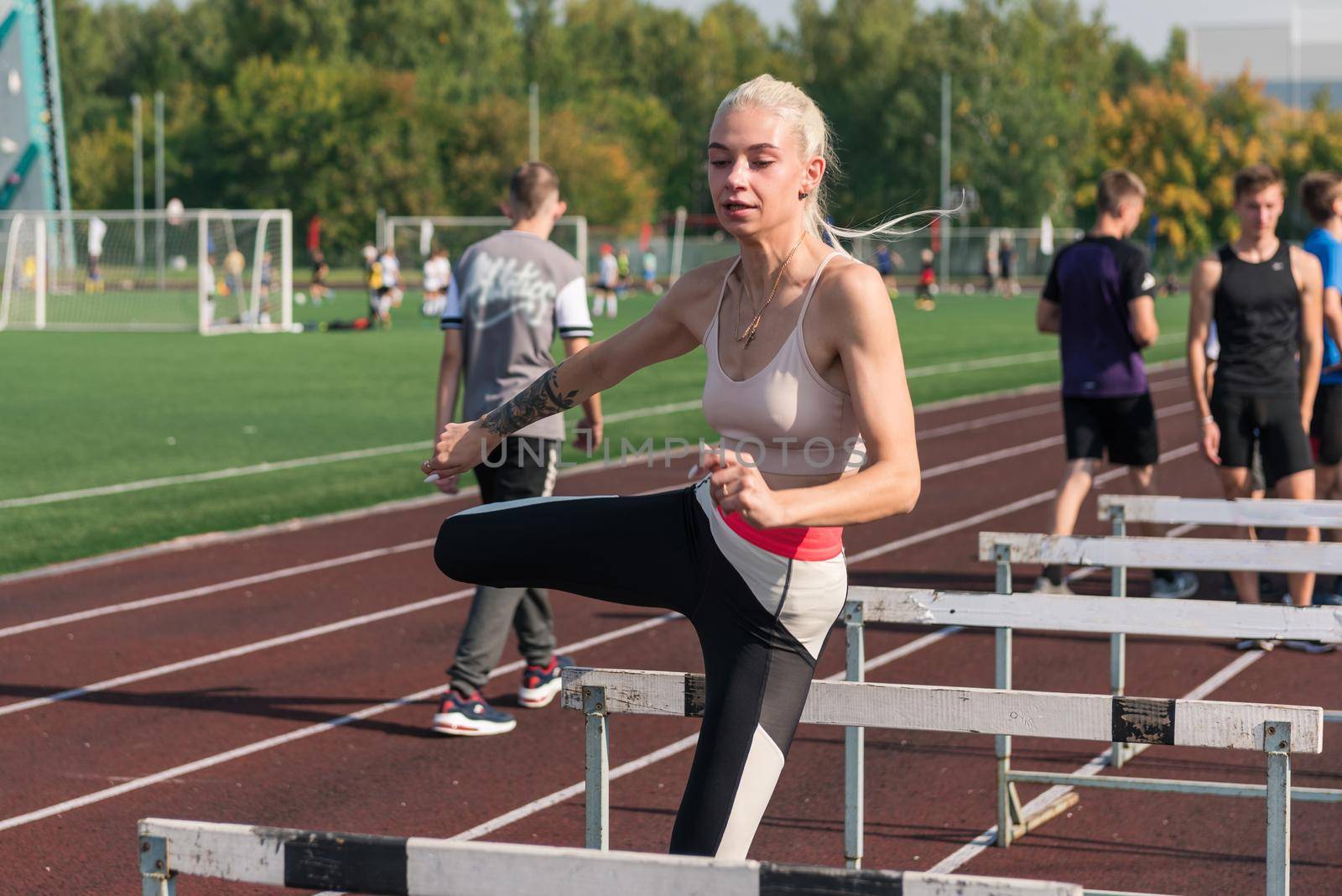Young woman athlete runnner is exercising hurdles at the stadium outdoors