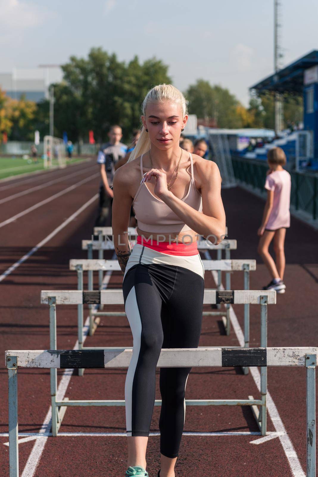 Young woman athlete runnner is exercising hurdles at the stadium outdoors