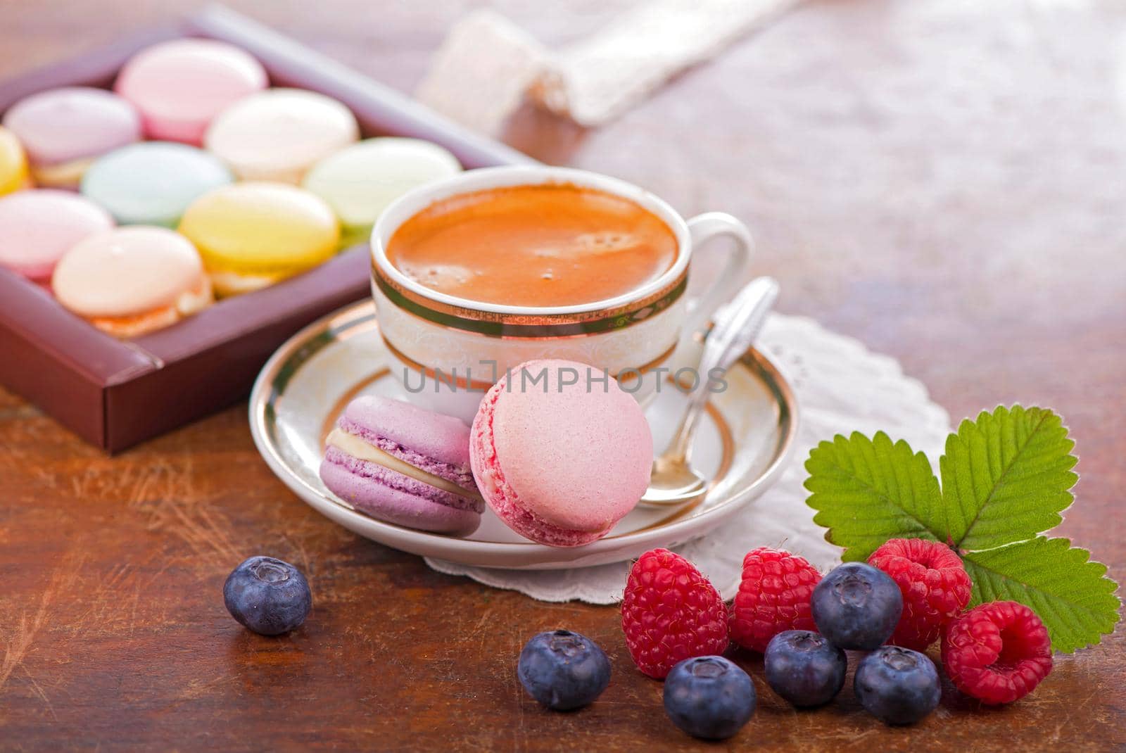 Macaroon with berries cookies and a cup of coffee on a wooden