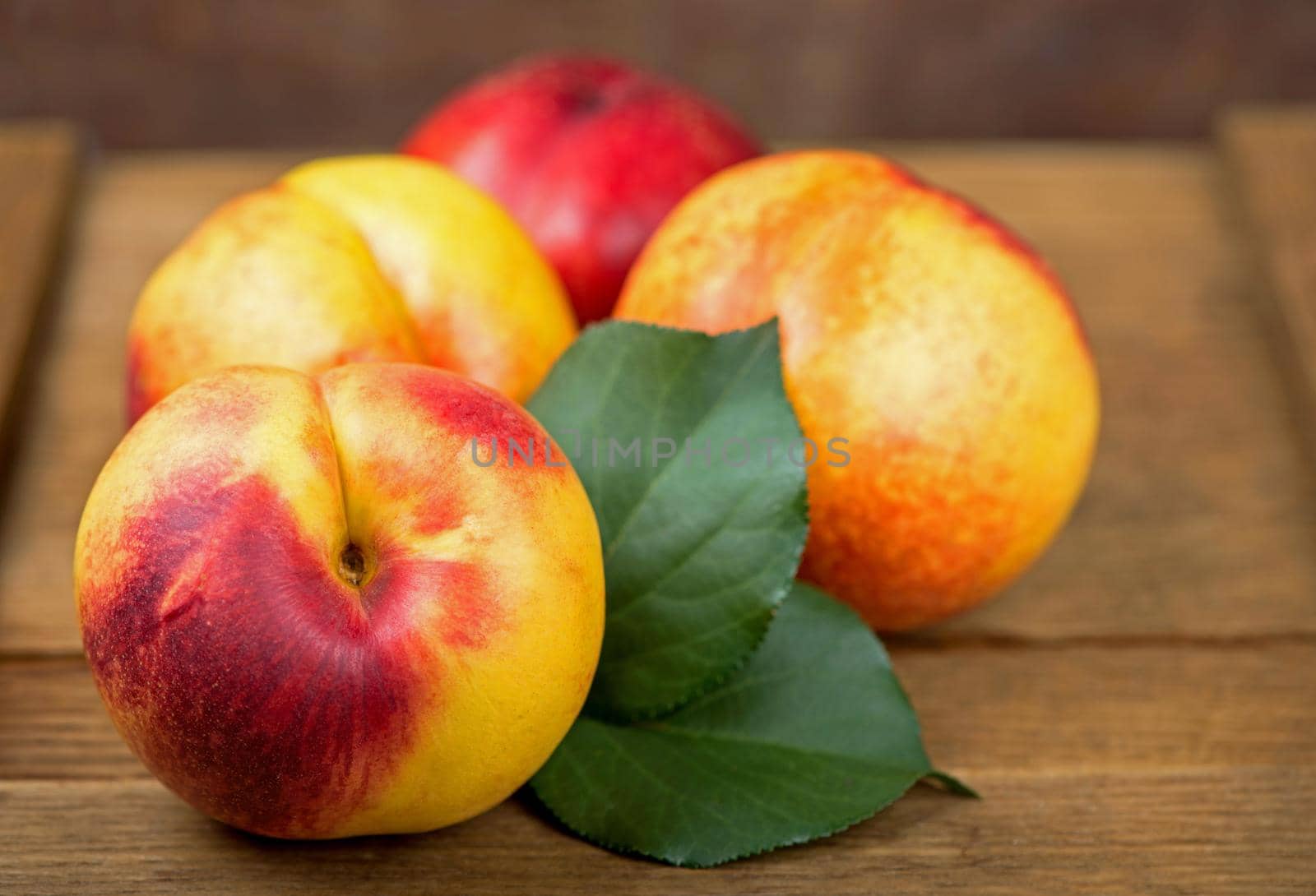 fresh nectarines with leaves on wooden background. by aprilphoto