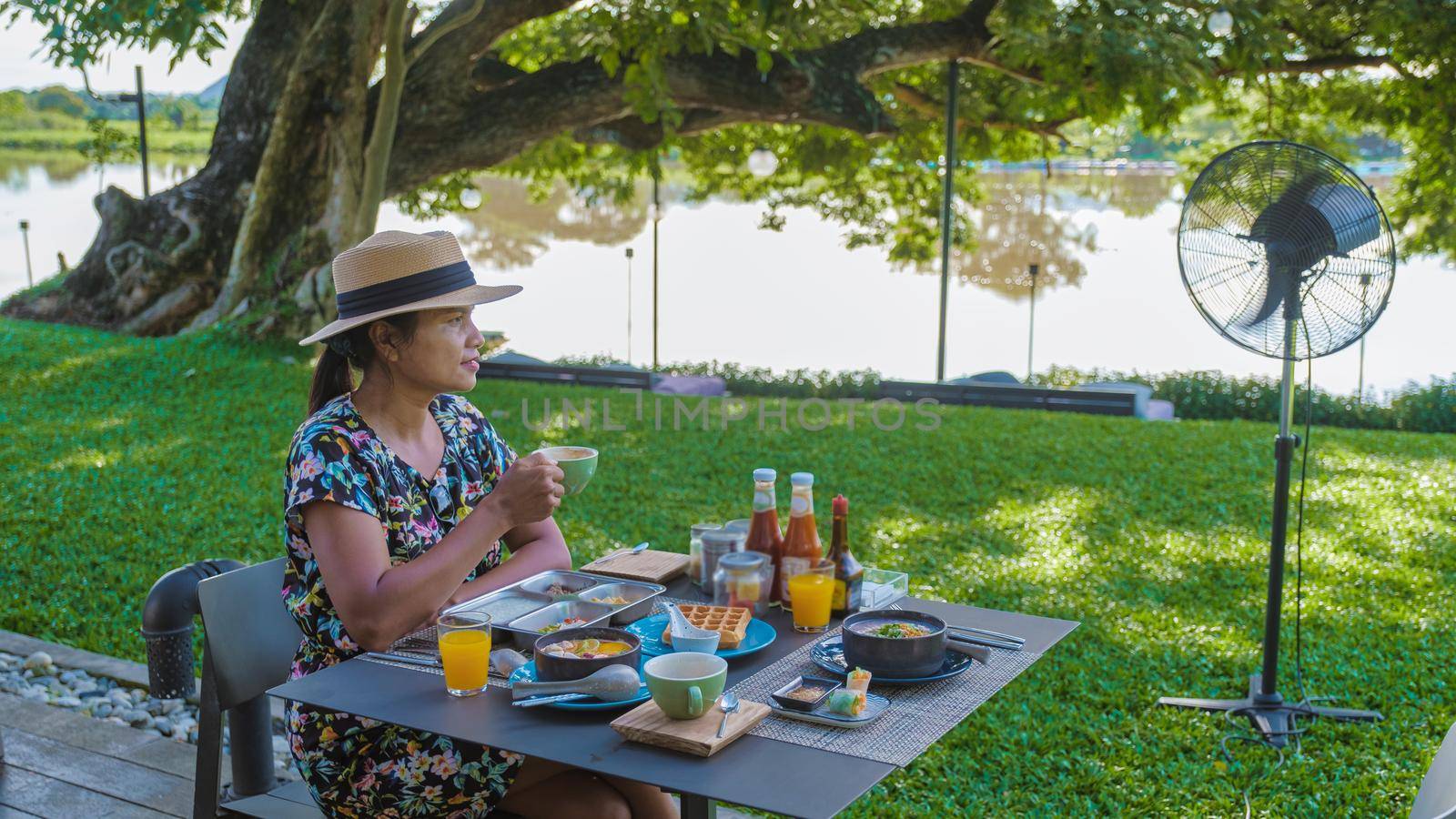 Luxury Asian breakfast on a table by the River Kwai in Thailand. Breakfast with rice soup, eggs, and salad, Asian women having breakfast