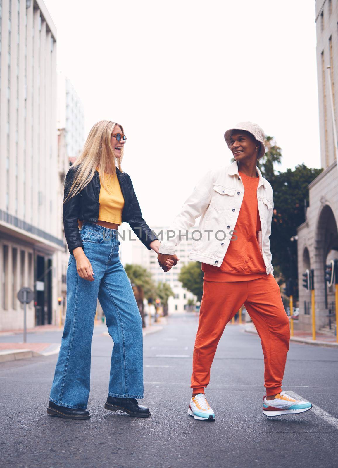 Happy interracial couple with fashion clothing in a urban city street with a smile and love. Trendy, stylish or punk man and woman walking in a town road with funky, edgy and style together.