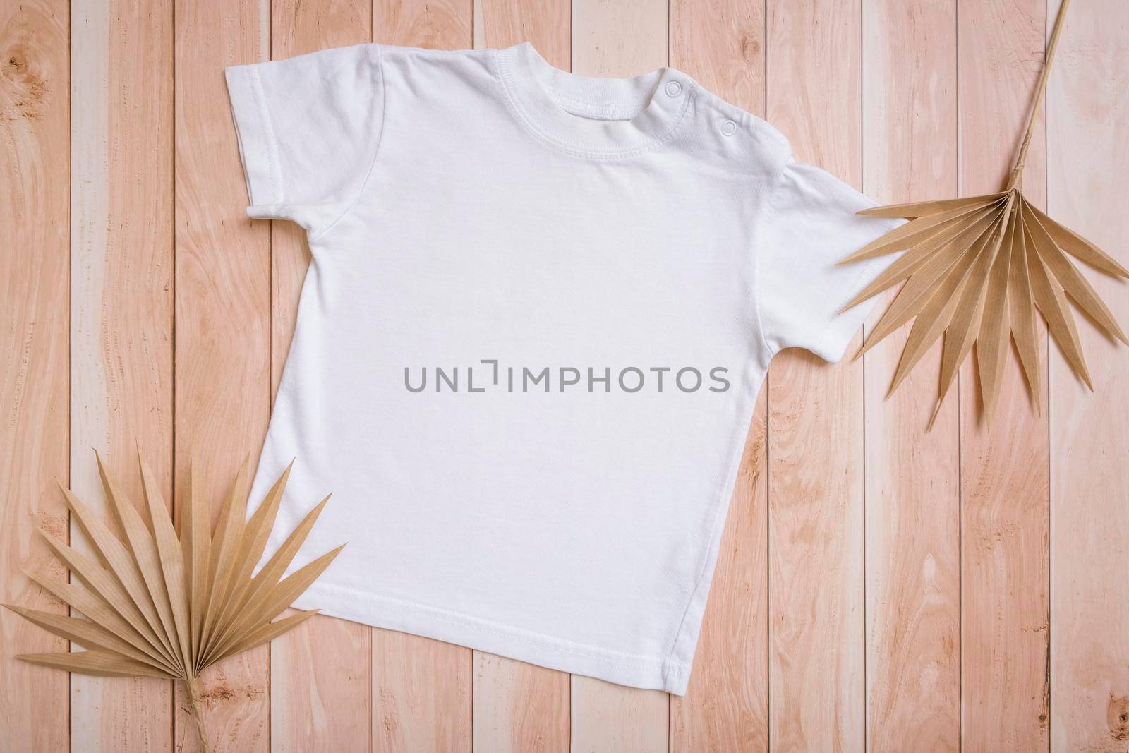 White baby t-shirt top view. Mock-up for logo, text or design on wooden background. Flat lay child clothes by ssvimaliss