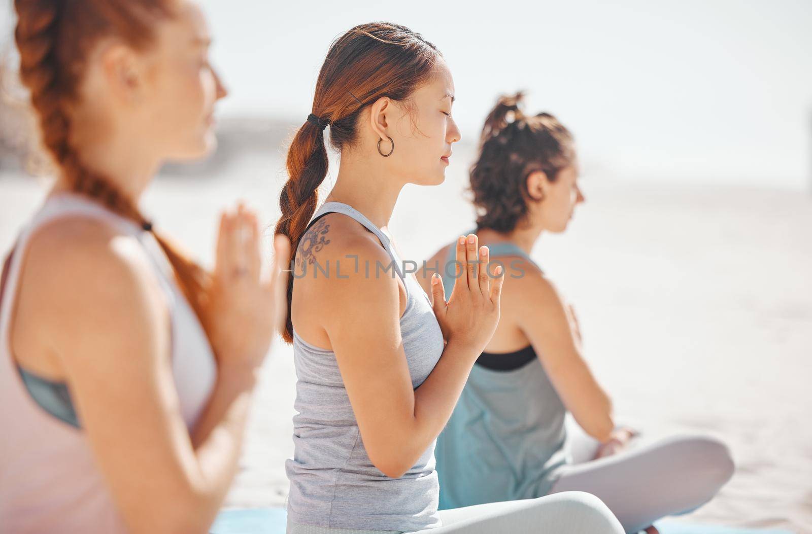 Women doing meditation class for wellness on beach, spiritual training exercise for calm and motivation for healthy lifestyle at the ocean in nature. Yoga group on summer travel holiday in Mexico.