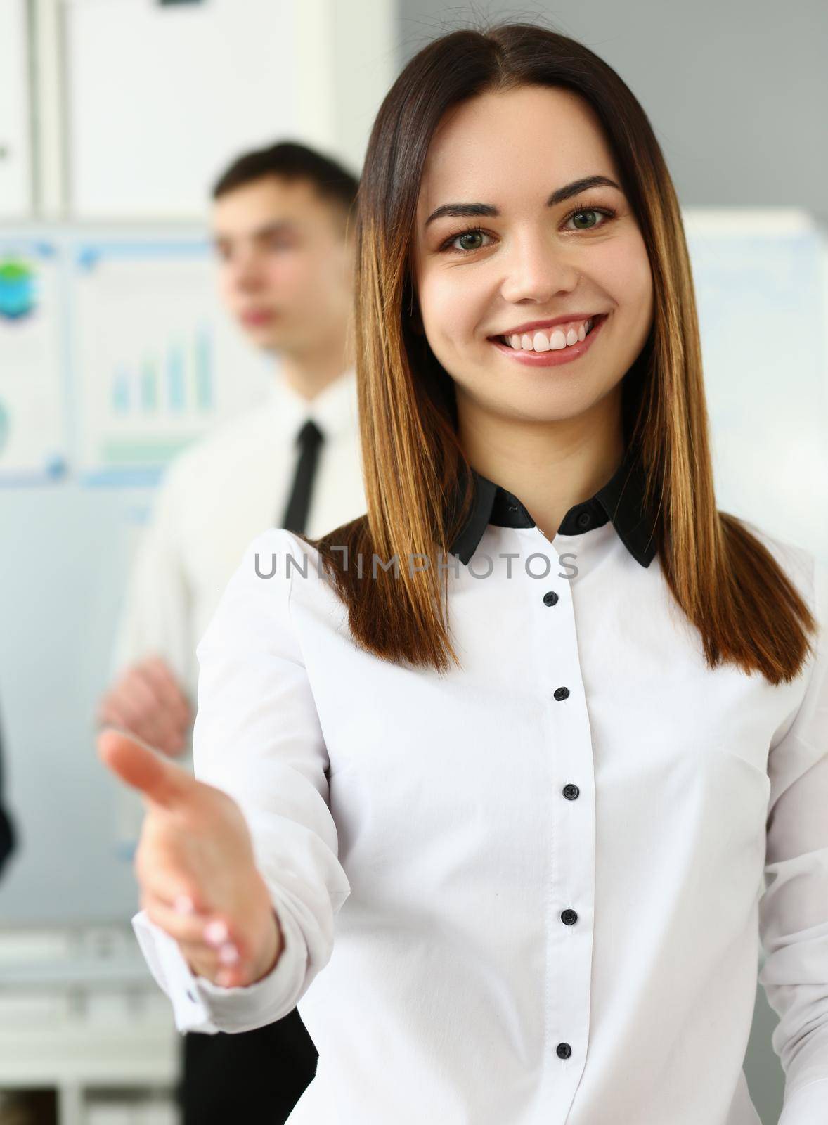 Smiling young business woman politely greets company office. Business consultant and team
