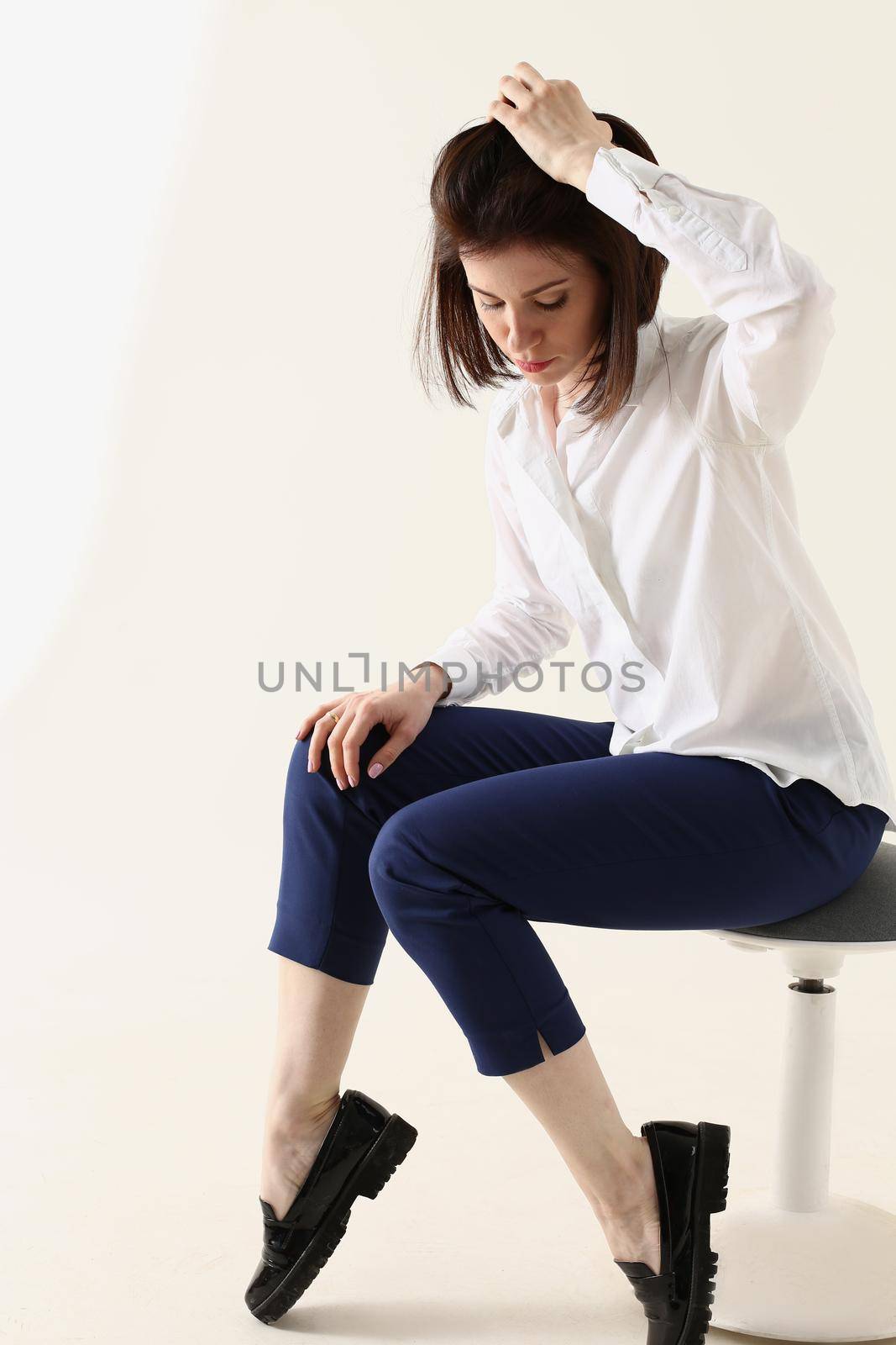 Woman in bad mood, bored and sad, sits on chair and puts hands on head. Woman in depression concept