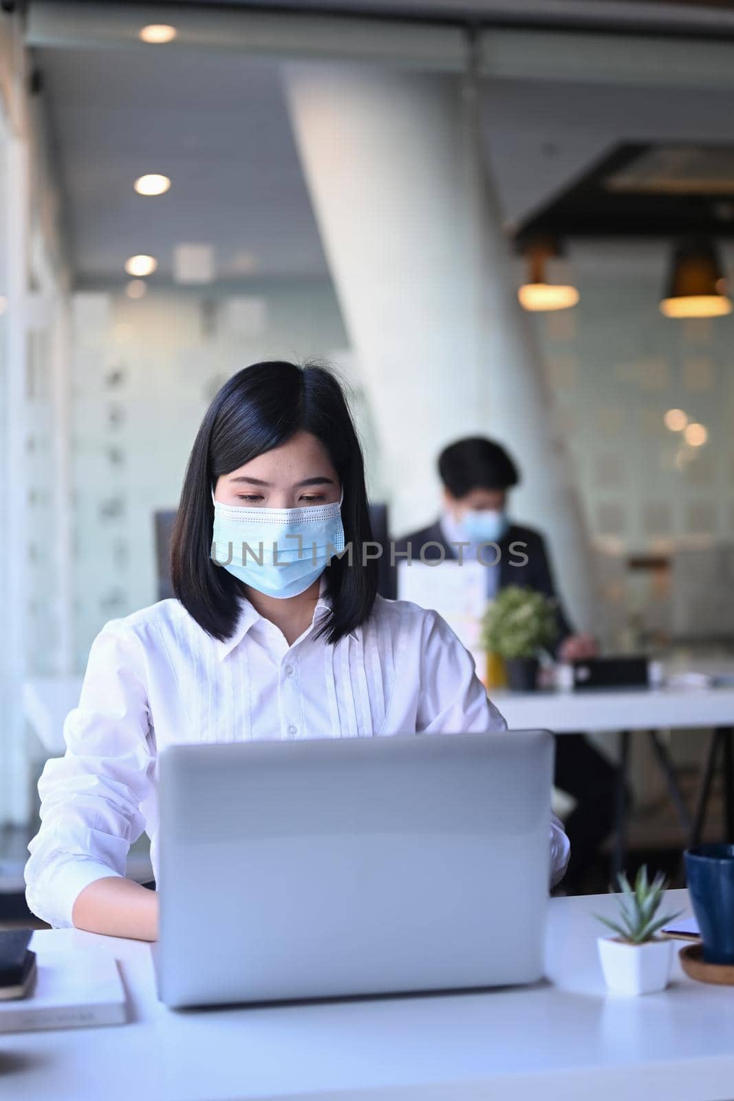 Asian businesswoman wearing protective mask and working in office. by prathanchorruangsak