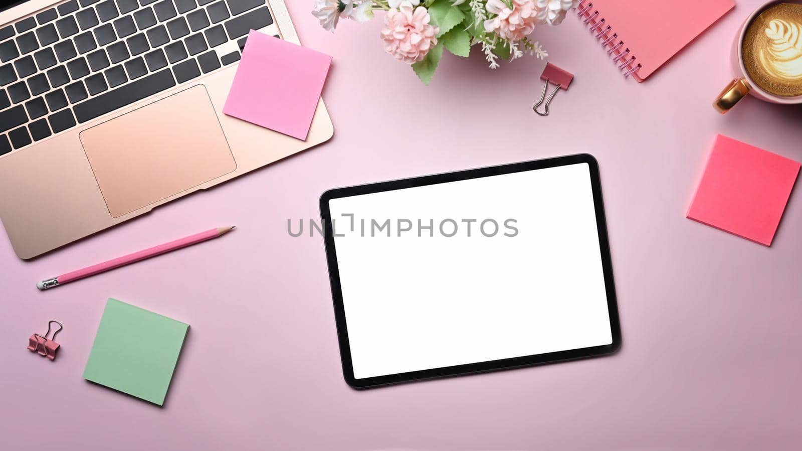Top view female workspace with digital tablet, laptop and colorful sticky notes on pink background. by prathanchorruangsak