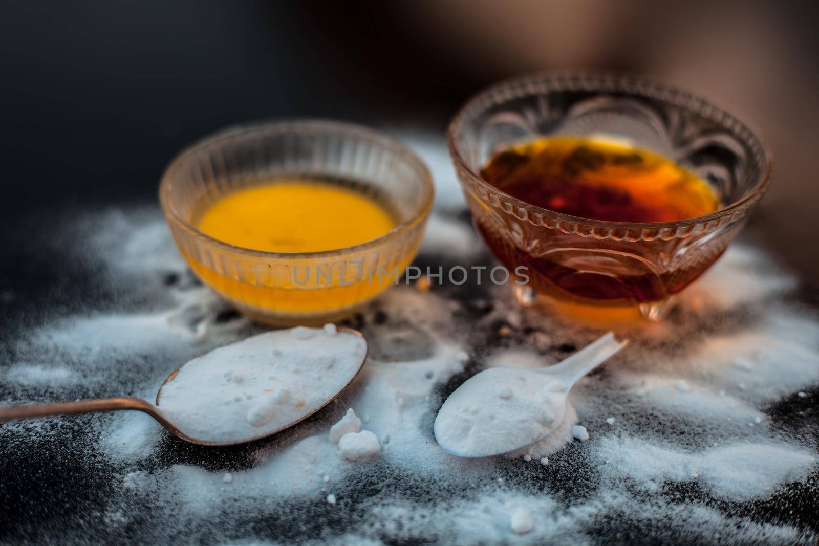 Baking soda face mask in a glass bowl on wooden surface along with baking soda powder and honey for Dark lips. Horizontal shot.