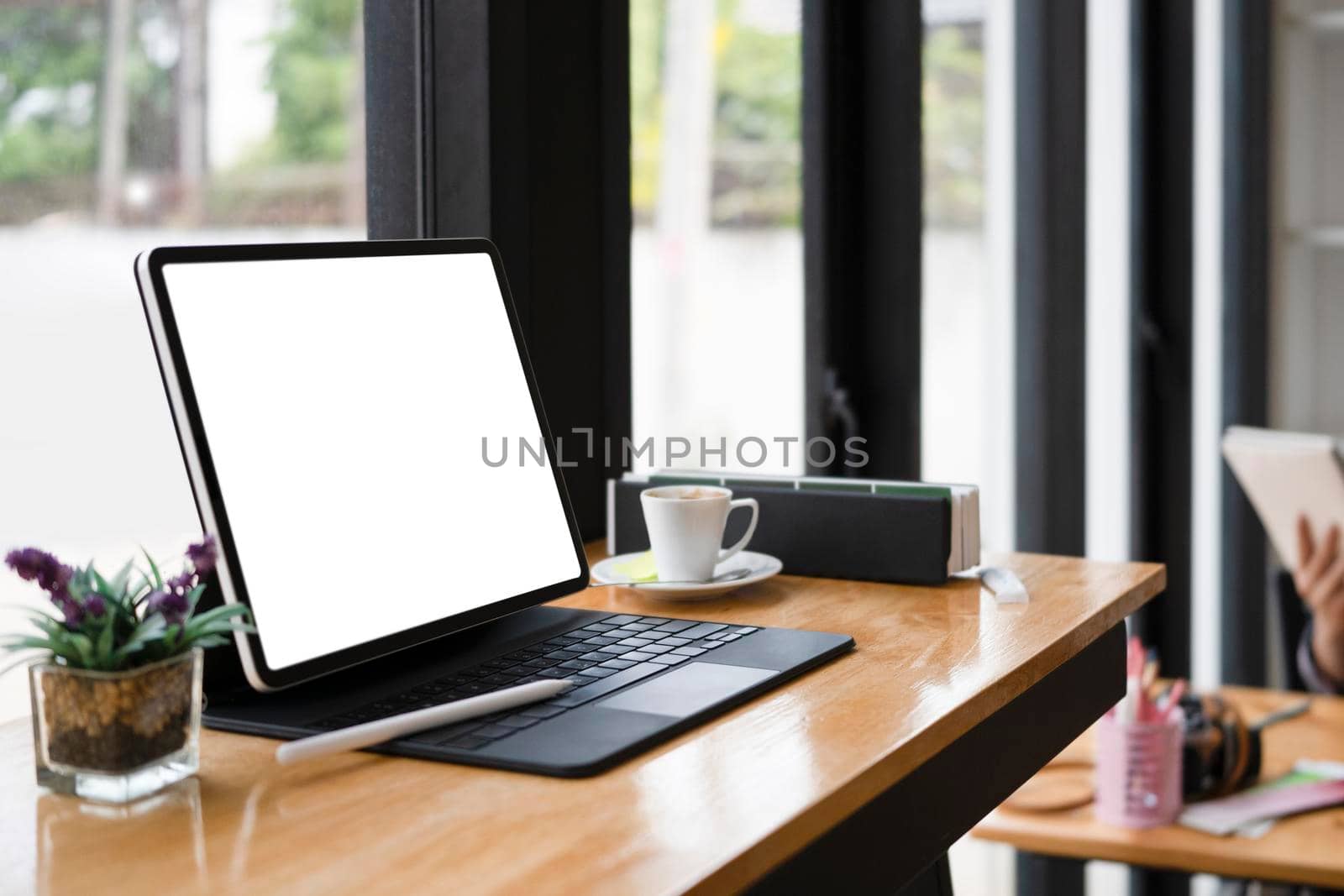 Computer tablet with white screen, coffee cup and book on wooden table. by prathanchorruangsak