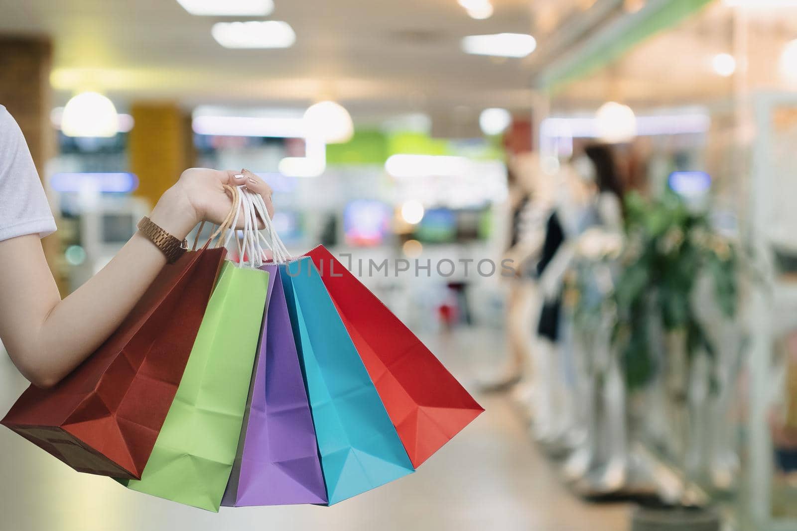 Young woman holding colorful shopping bags while doing shopping in the mall.