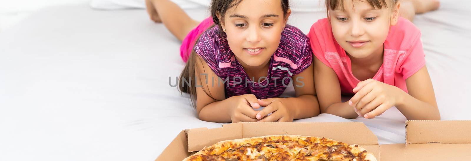 Two little girls eating pizza at home.