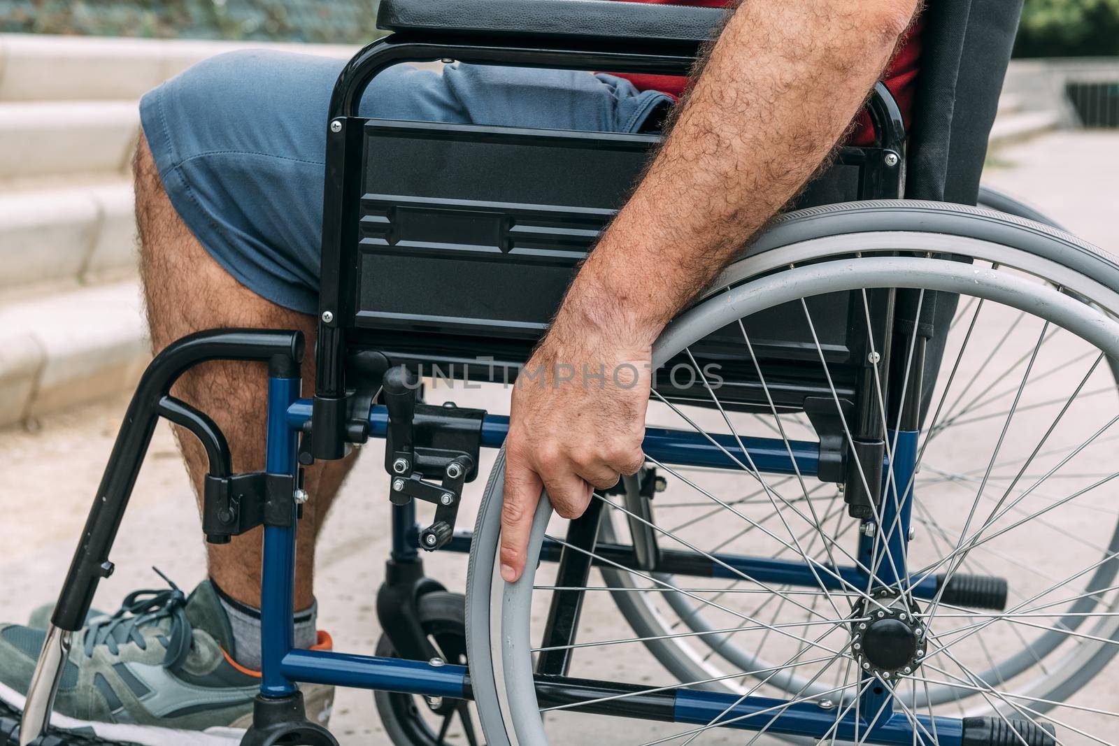 Close up of disabled man sitting in a wheelchair, his hand is holding the wheel