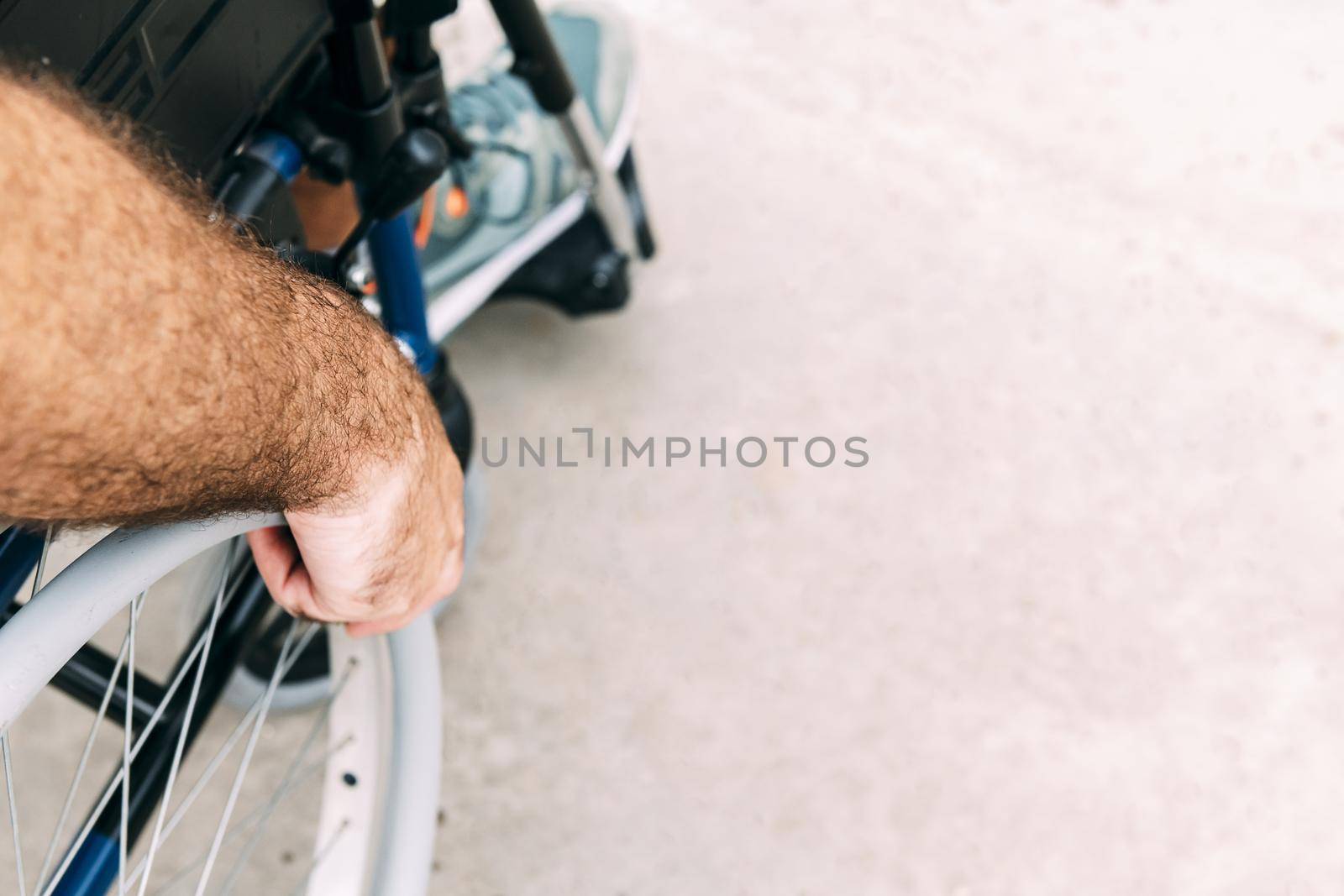 Close up of disabled man sitting in a wheelchair, he holds his hand on the wheel