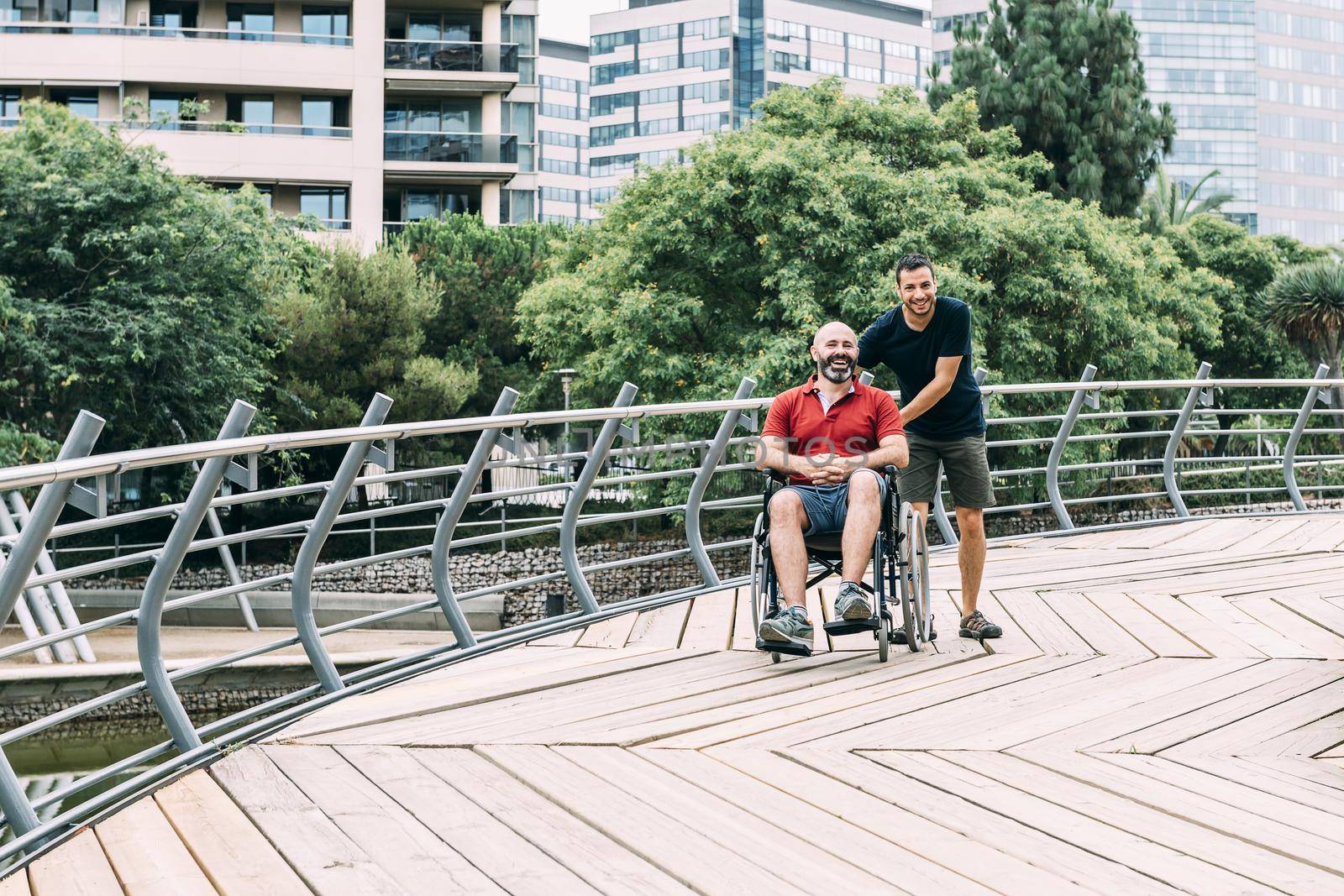 man in wheelchair walking at park with a friend by raulmelldo