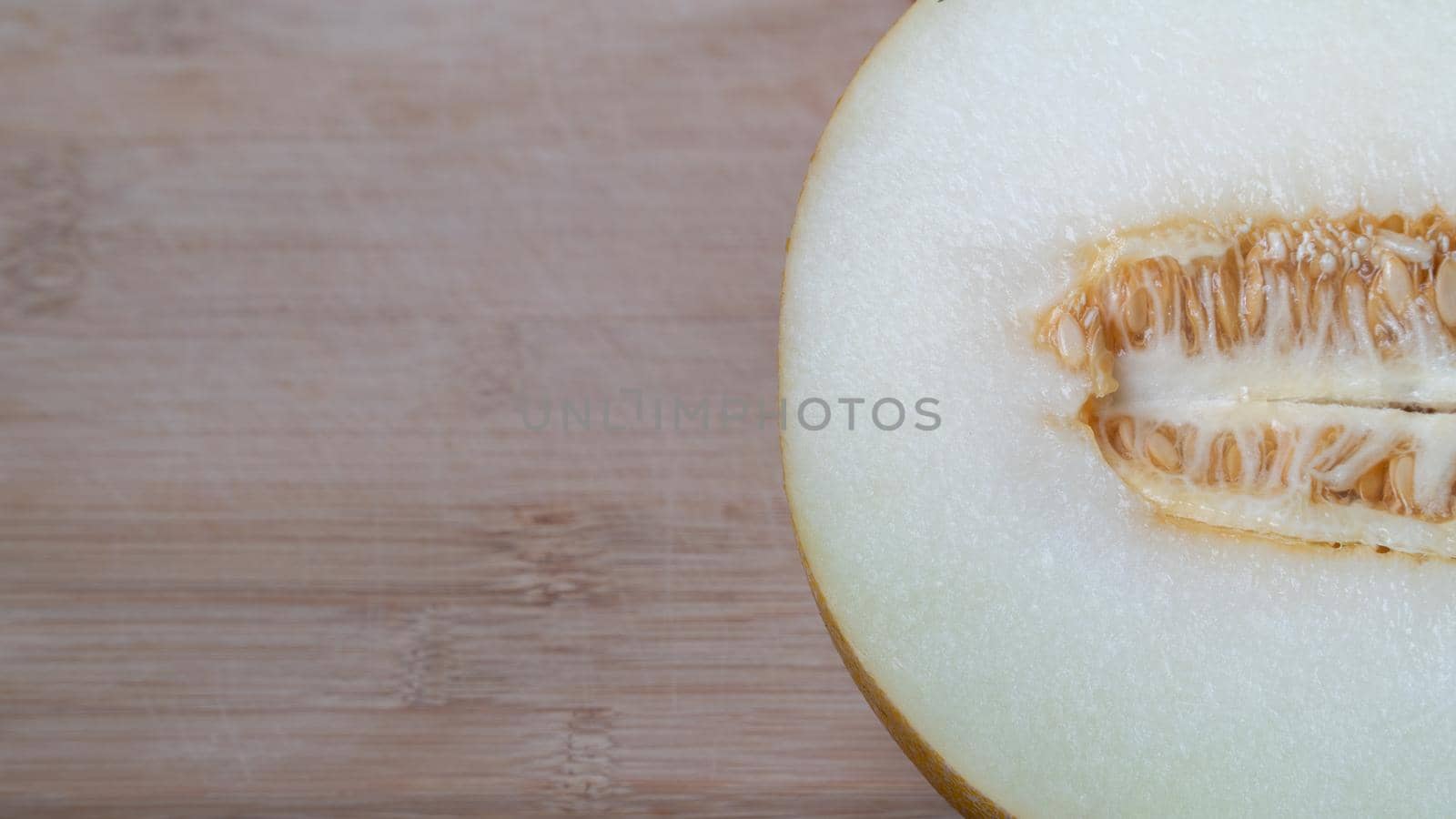 Half a melon fruit in section on a wooden background place for text by voktybre