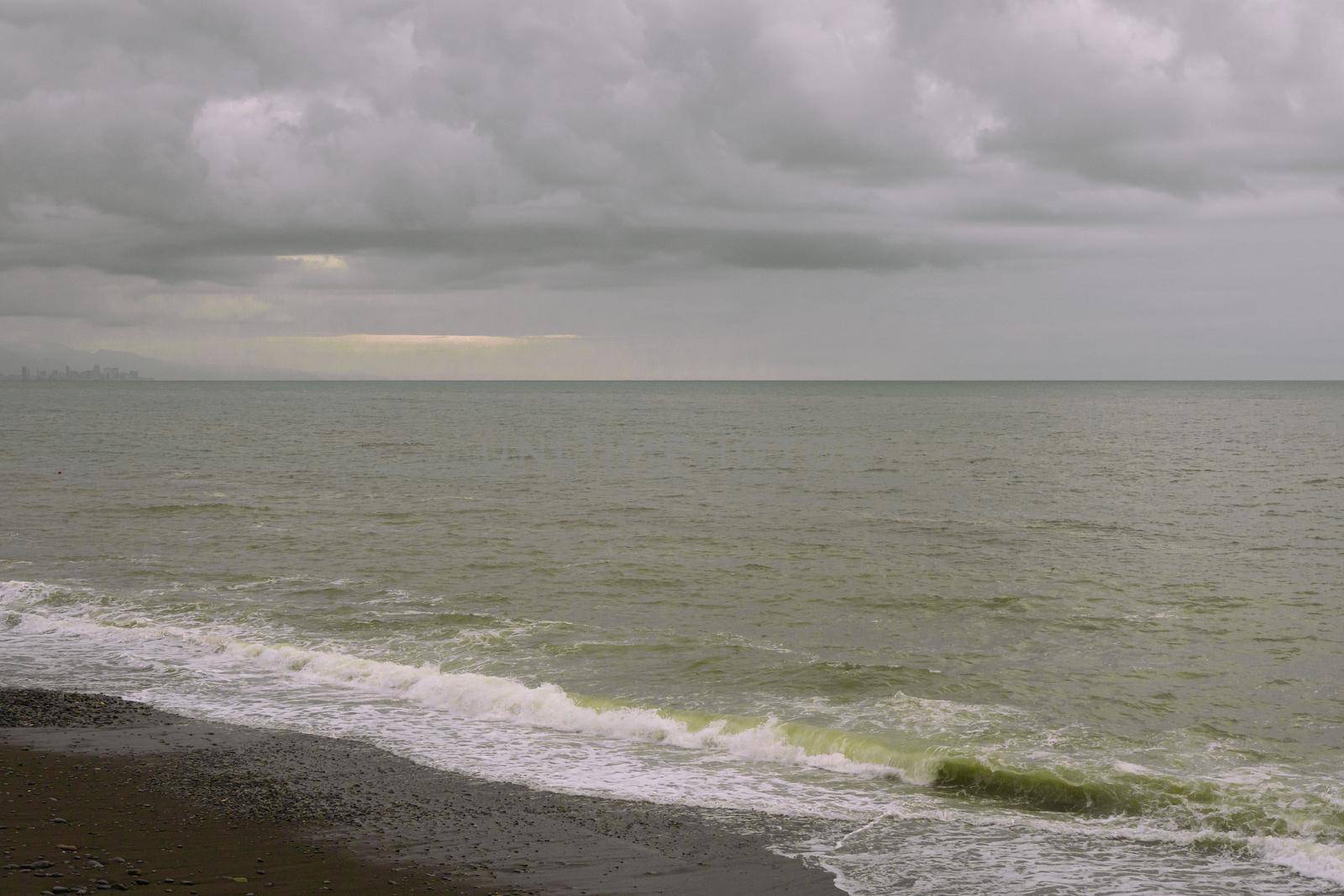 Sea shore with pebbles, wet sea pebbles on the beach and quiet sea surf. Restless sea and waves