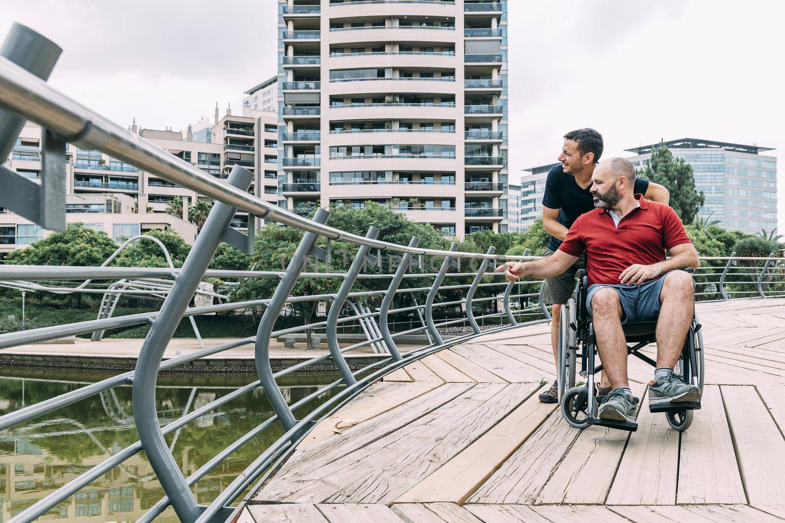 disabled man in a wheelchair talking to his friend during a walk, concept of friendship and integration of people with disabilities and reduced mobility problems, vertical photo