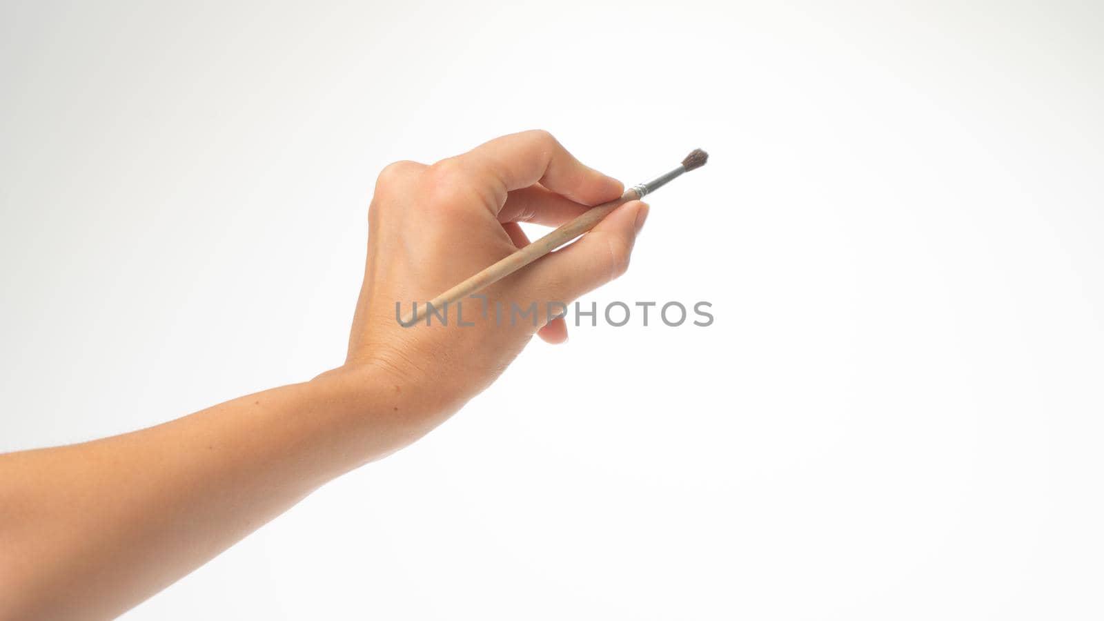 A woman's left hand holds a brush to draw on a white background