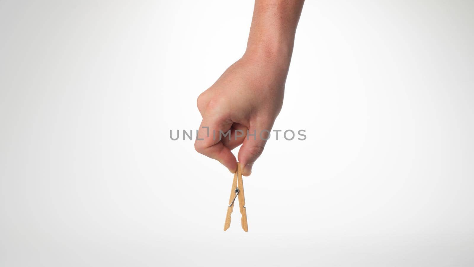 A man's hand holds an open wooden clothespin on top by voktybre