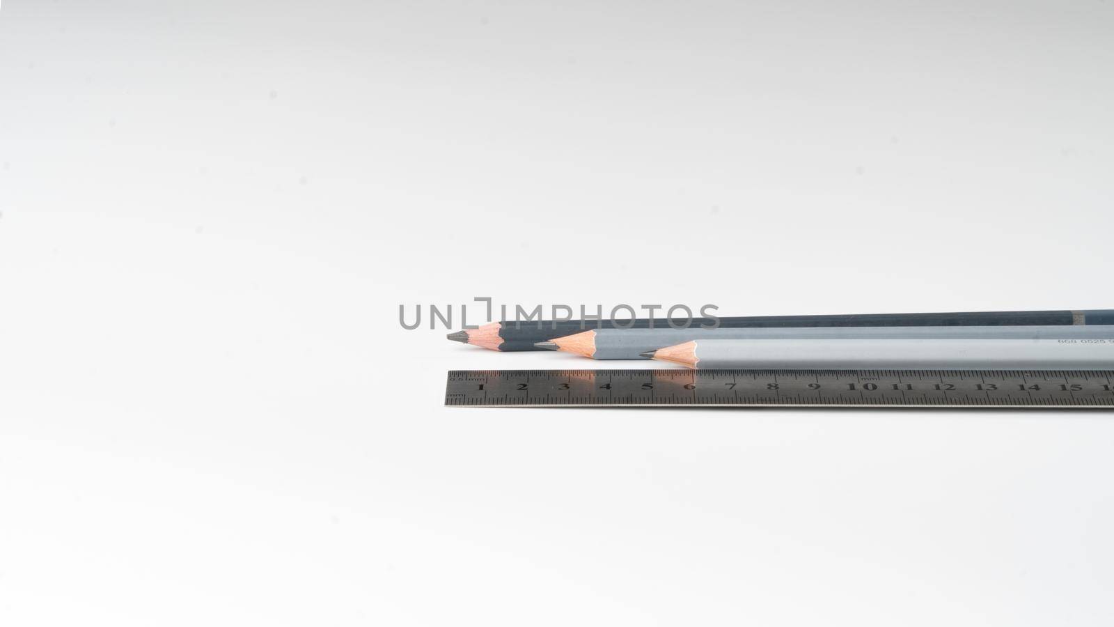 Wooden simple pencils and a metal ruler horizontally on a white background. High quality photo