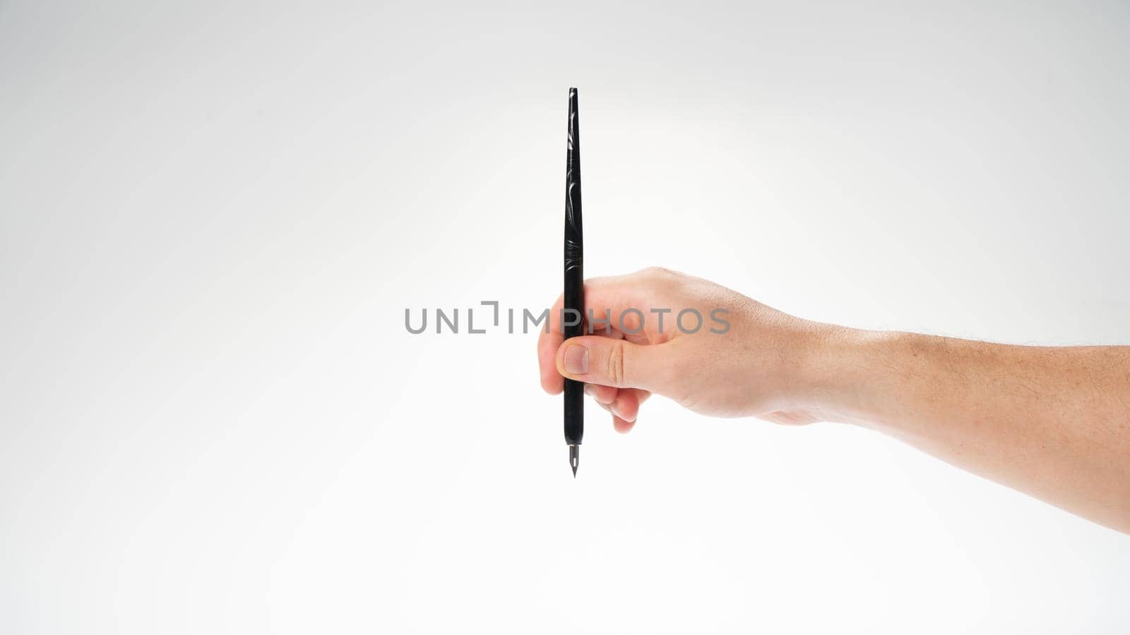 male right hand holds a calligraphy pen on a white background, gesture drops into the inkwell. High quality photo